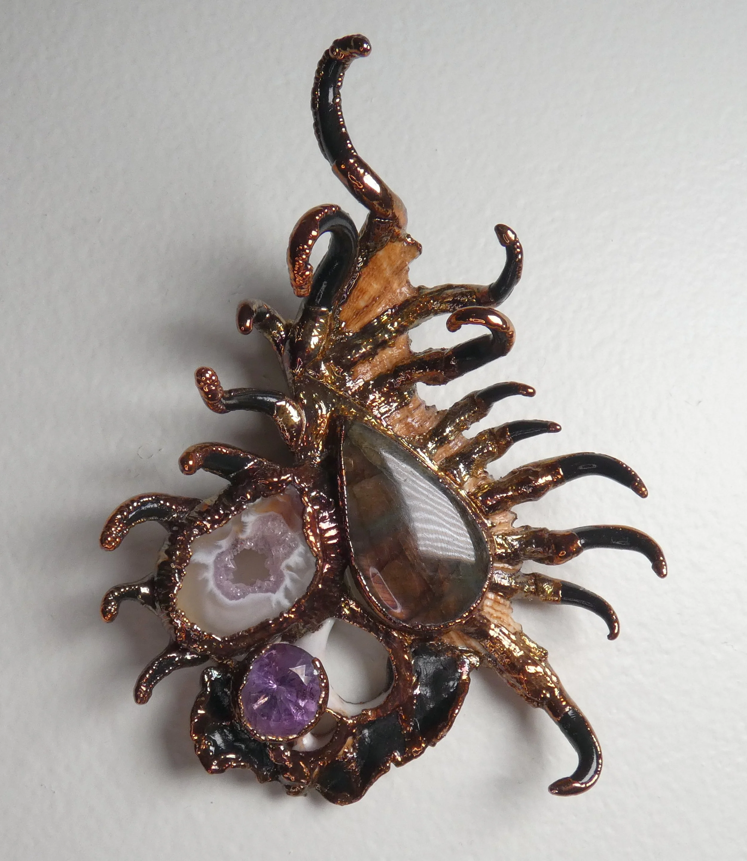 Symbiont 039 (Wall sculpture with keyhole slot): seashell slice, labradorite, Occo agate, faceted lab alexandrite, epoxy clay, electroformed copper. 5” H x 4” W x 2” D. Available $900.