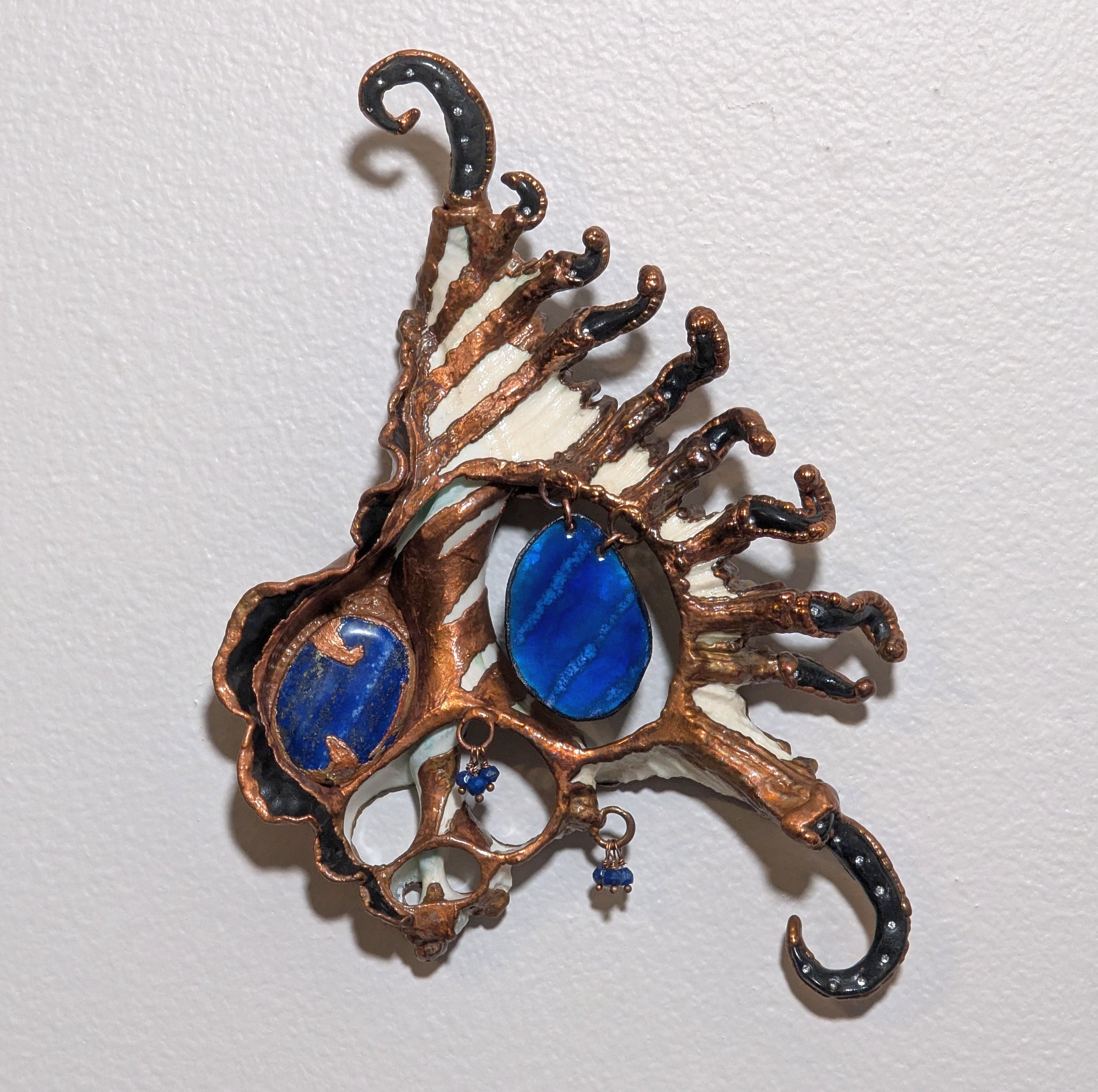 Symbiont 023 (Wall sculpture with keyhole slot): seashell slice, lapis lazuli, enameled copper, rhinestones, epoxy clay, electroformed in copper. 9" H x 6" W x 2" D. Available $1000.