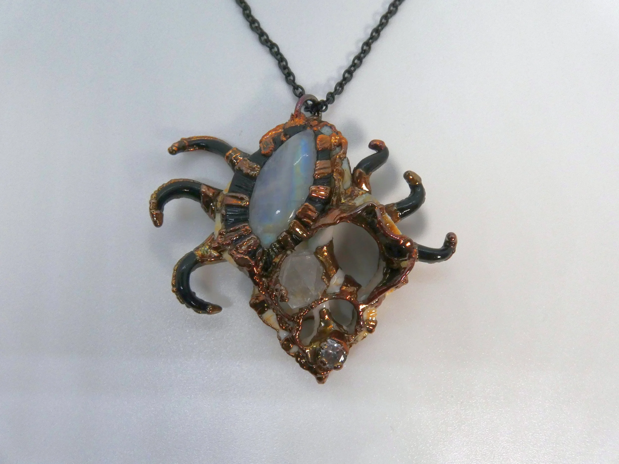 Symbiont 037 (Pendant): seashell slice, moonstone, Herkimer diamond quartz, cubic zirconia, epoxy clay, electroformed in copper. 2.5” H x 1.75” W. Available $300.