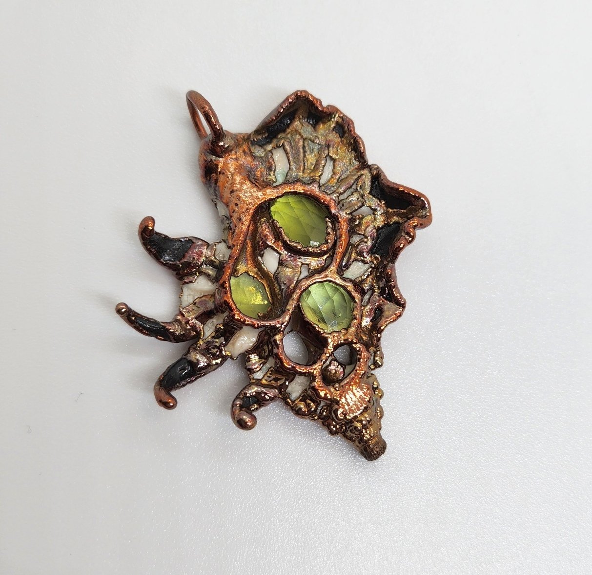 Symbiont 027 (Pendant): seashell slice, faceted peridot, epoxy clay, electroformed in copper. 1.5”H x 1” W. In private collection.