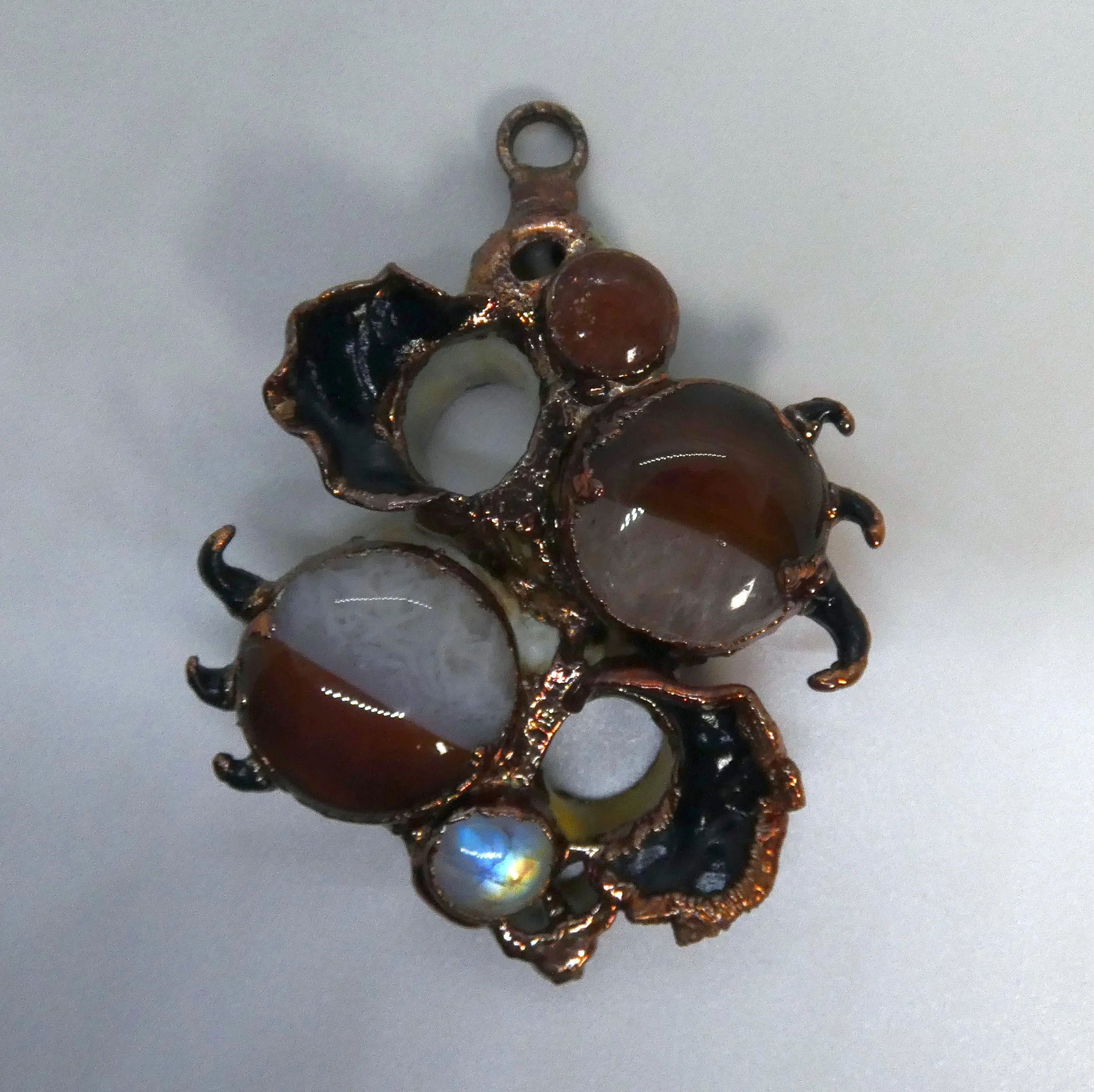 Symbiont 036 (Wall sculpture with sculpture loop): seashell slices, agate pair, moonstone, sunstone, epoxy clay, electroformed in copper. 3.5” H x 2.5” W x 1” D. Available $450.