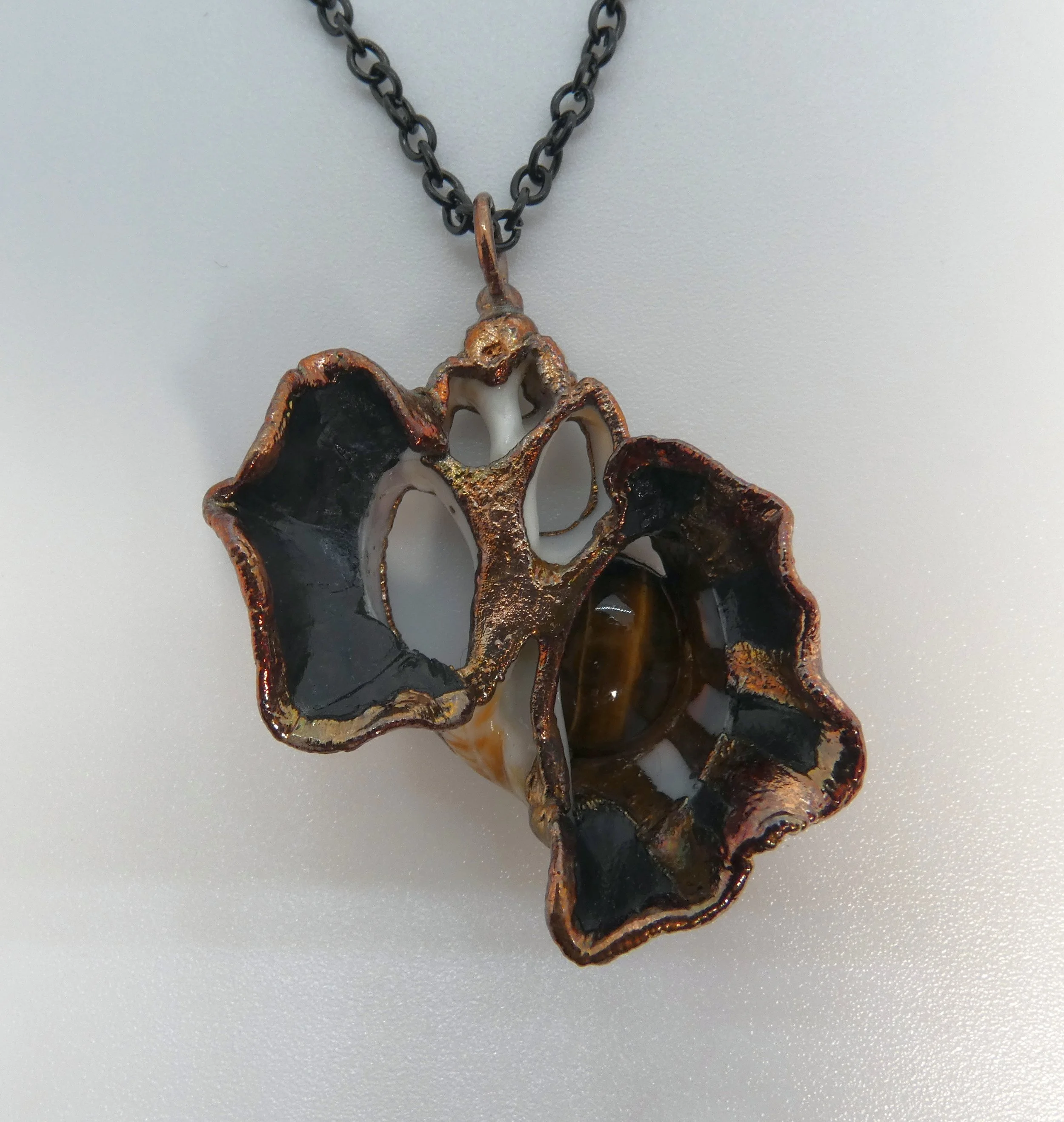 Symbiont 017 (Pendant): seashell slice, tiger eye, epoxy clay, electroformed in copper. 2.25” H x 2” W. Available $150.