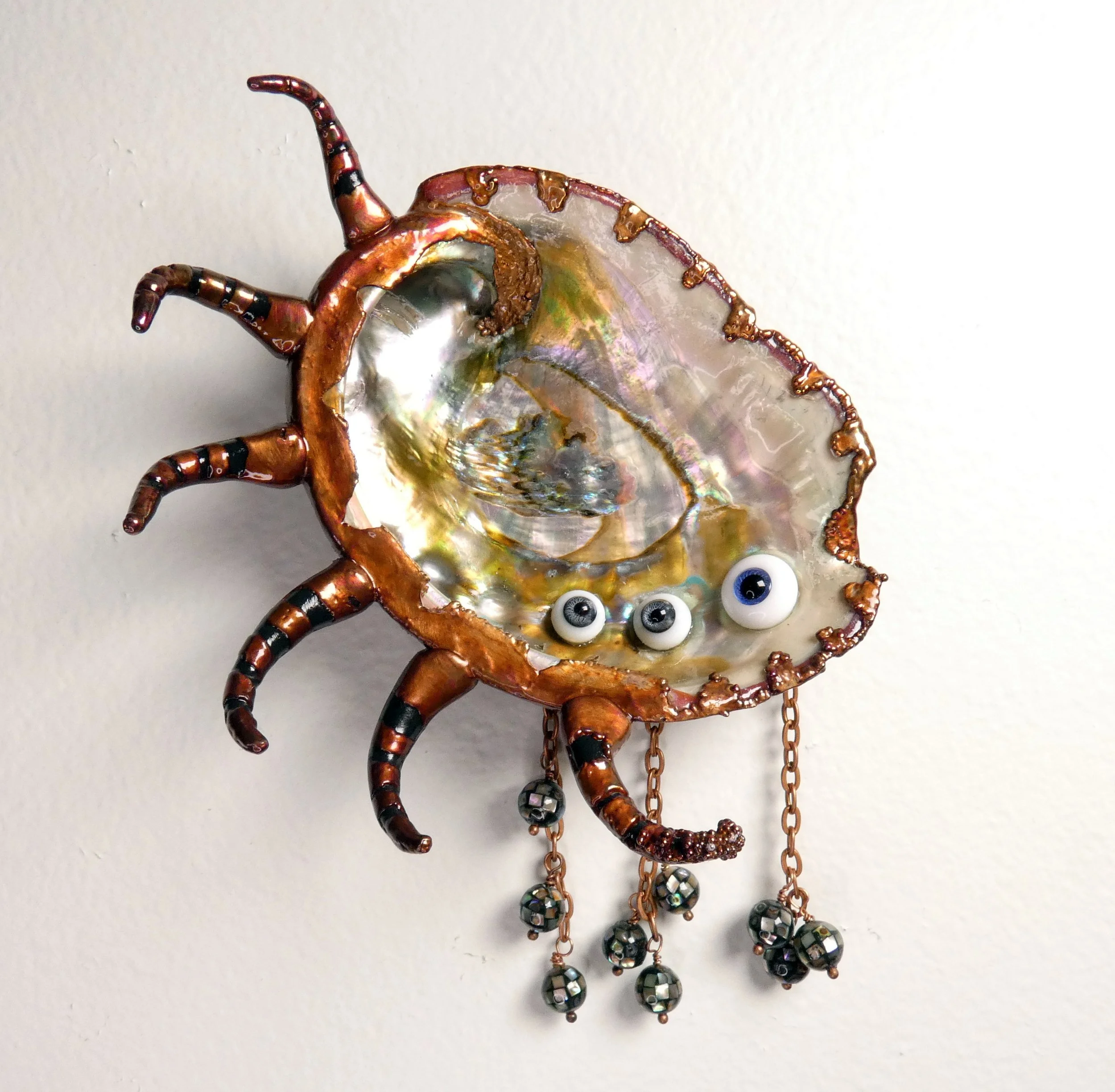 Symbiont 033 (Wall sculpture with keyhole slot): red lip abalone shell, vintage Lauscha glass doll eyes, epoxy clay, electroformed in copper with copper chain and abalone shell beads. 7” H x 4” W x 2” D. Available $1000.