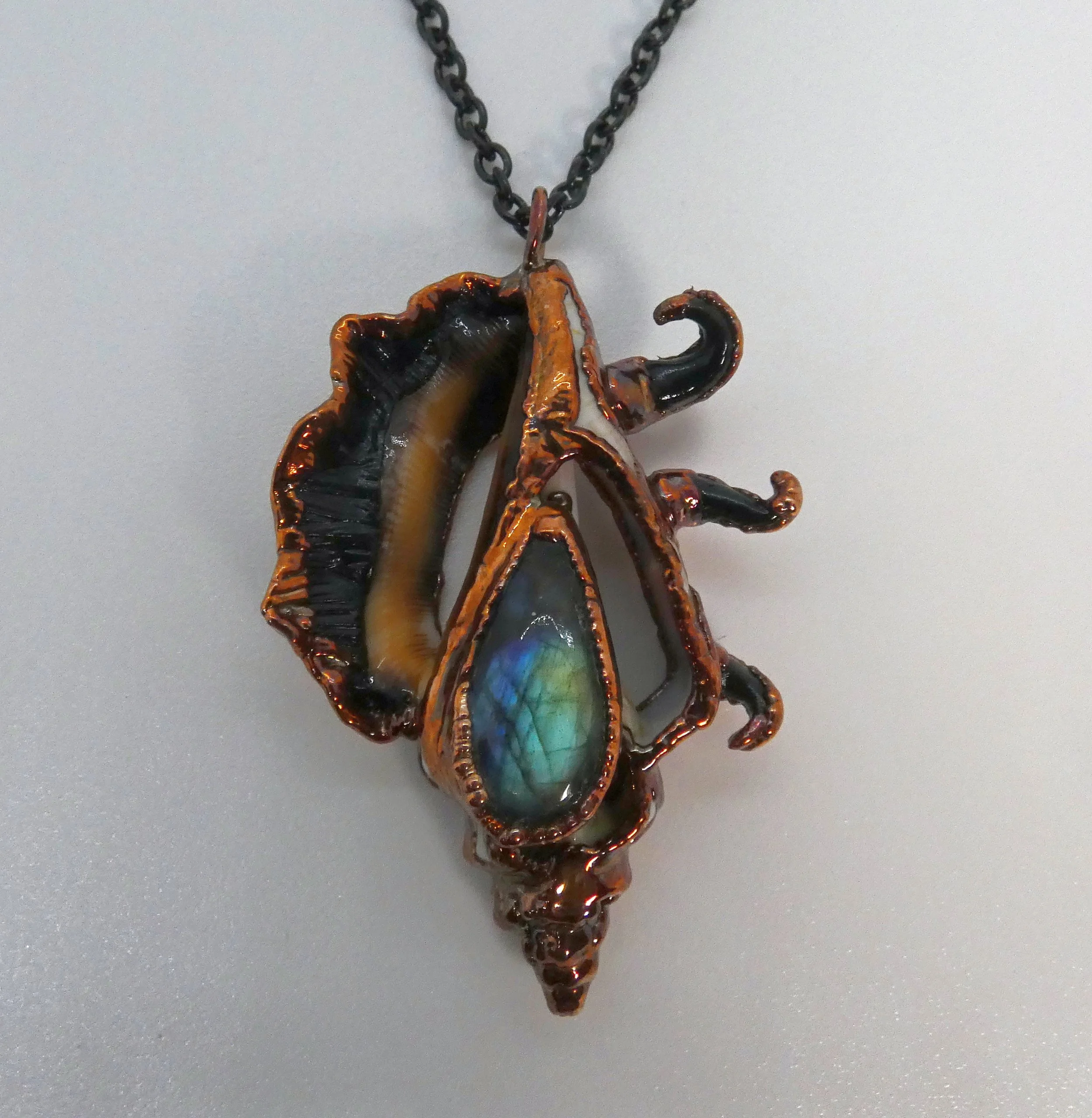 Symbiont 038 (Pendant): seashell slice, labradorite, epoxy clay, electroformed copper. 2.5” H x 1.75” W. In private collection.