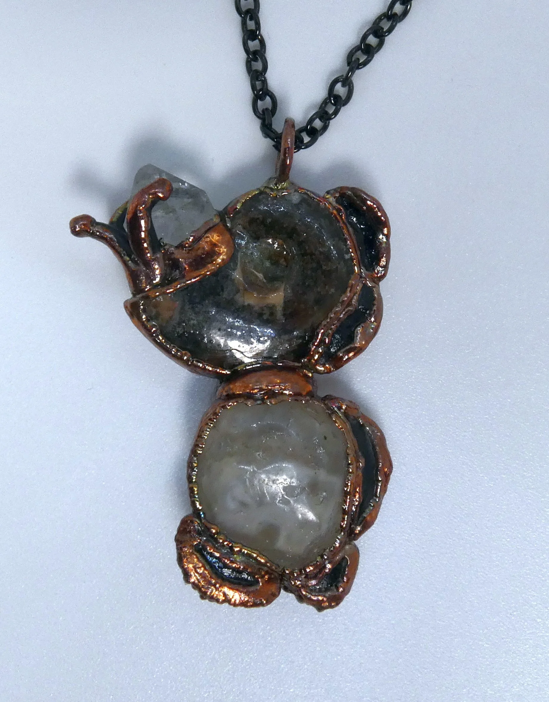 Symbiont 022 (Pendant): ammonite fossil, Herkimer diamond quartz point, enhydro agate with ancient water drop inside, epoxy clay, electroformed in copper. 2” H x 1” W. In private collection.