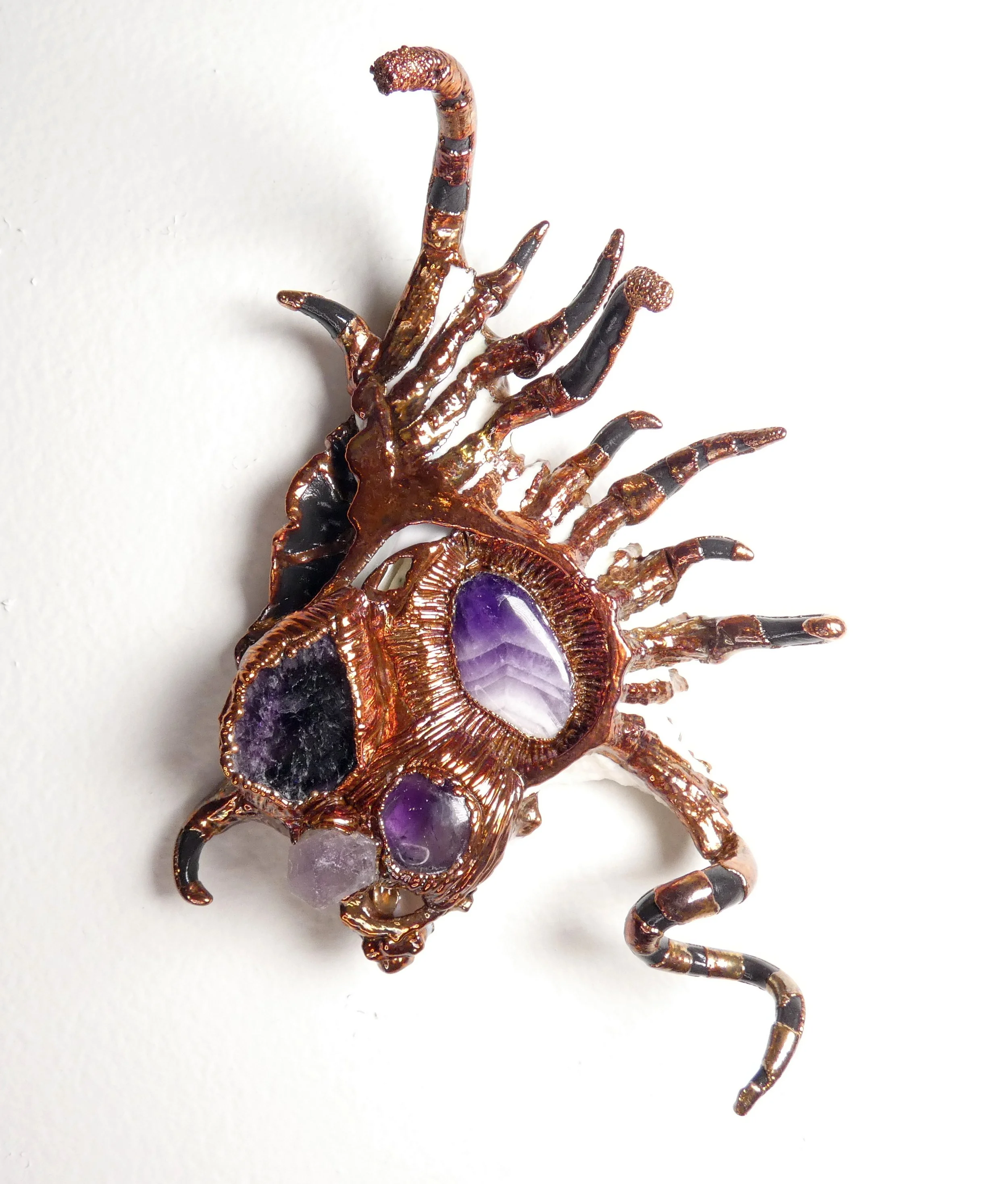 Symbiont 047 (Wall sculpture): seashell slice, amethyst tumble, chevron amethyst, amethyst crystal, amethyst Rough, epoxy clay, electroformed copper. 6" H x 5" W x 2” D. In private collection.