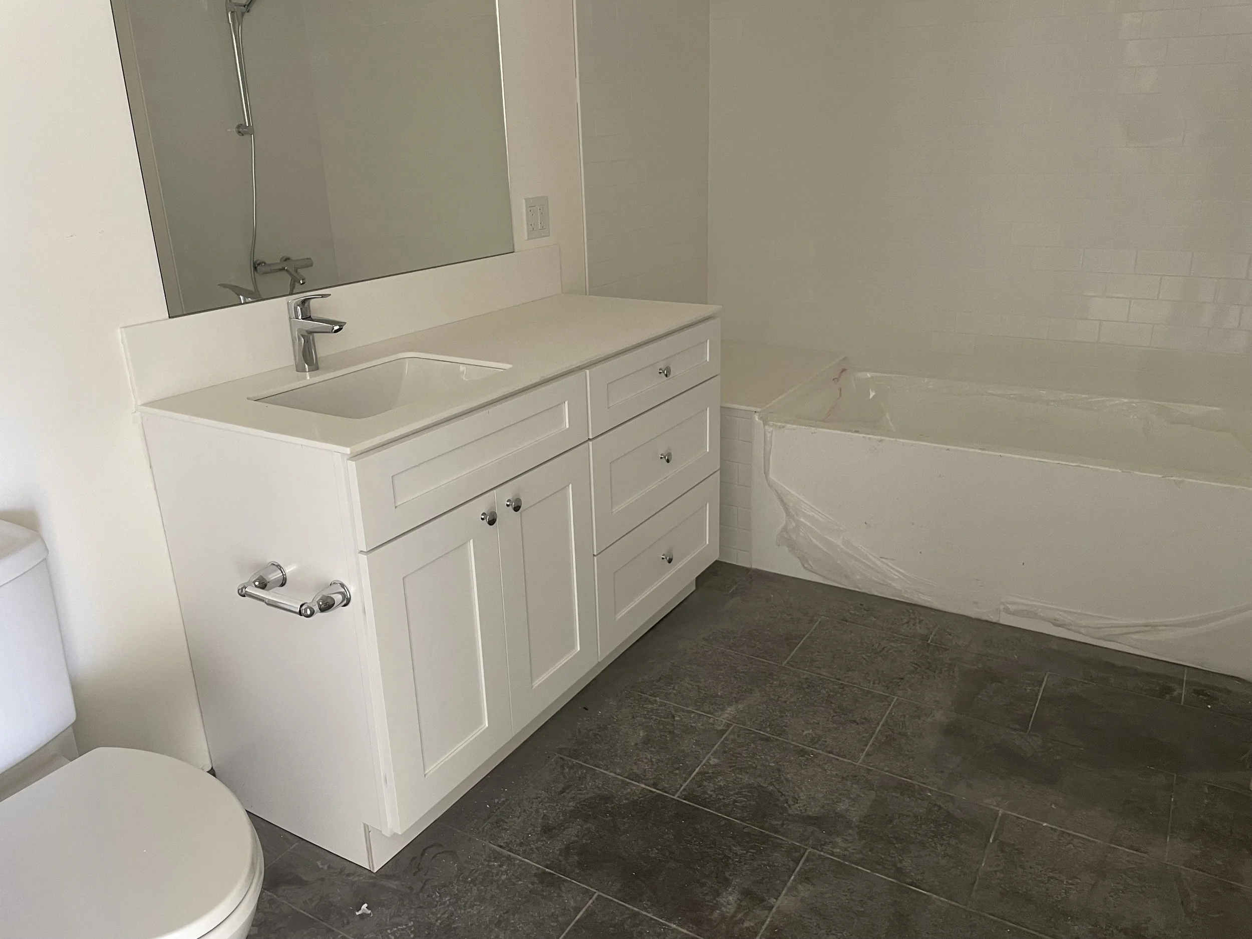 Bathroom with a white vanity, mirror, and bathtub under construction or renovation.