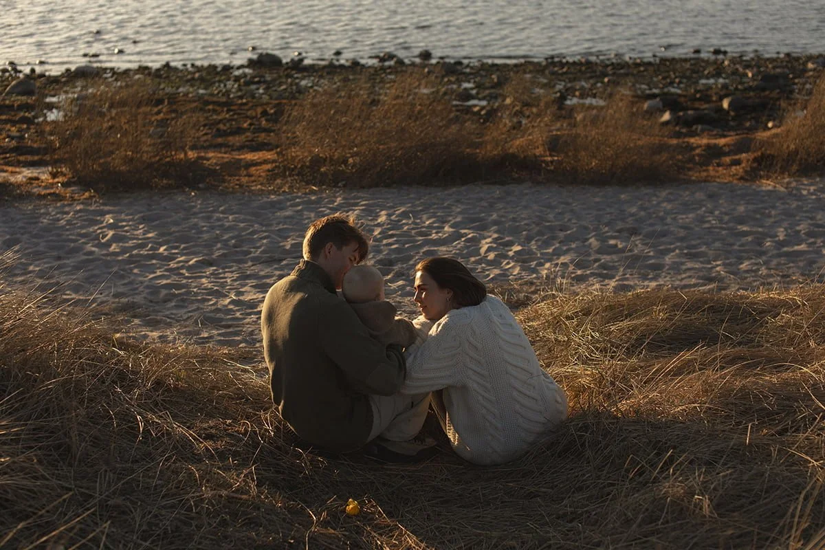 Familj sitter tillsammans vid havet i Lomma i varmt eftermiddagsljus.