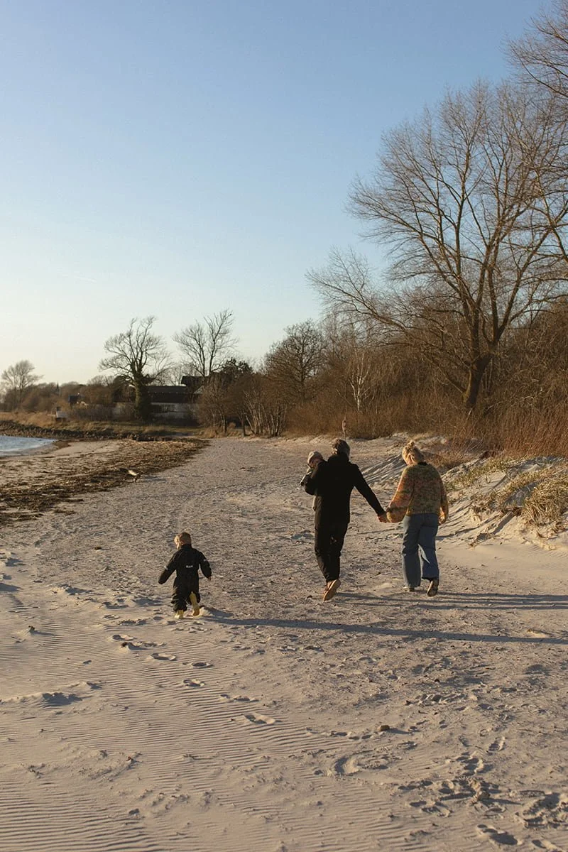 Familj med barn promenerar längs stranden i Bjärred under en solig vårdag i april.