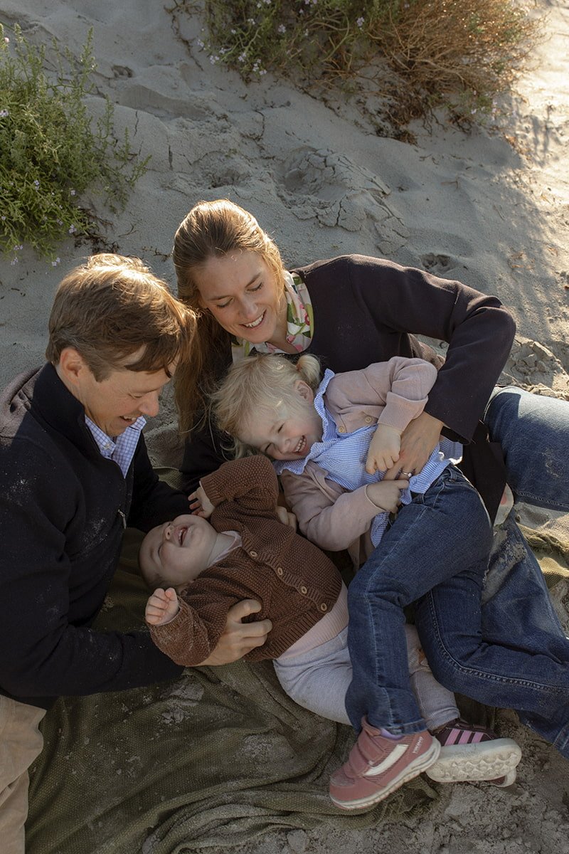 Familj sitter tillsammans på stranden i Lomma en solig morgon i september.