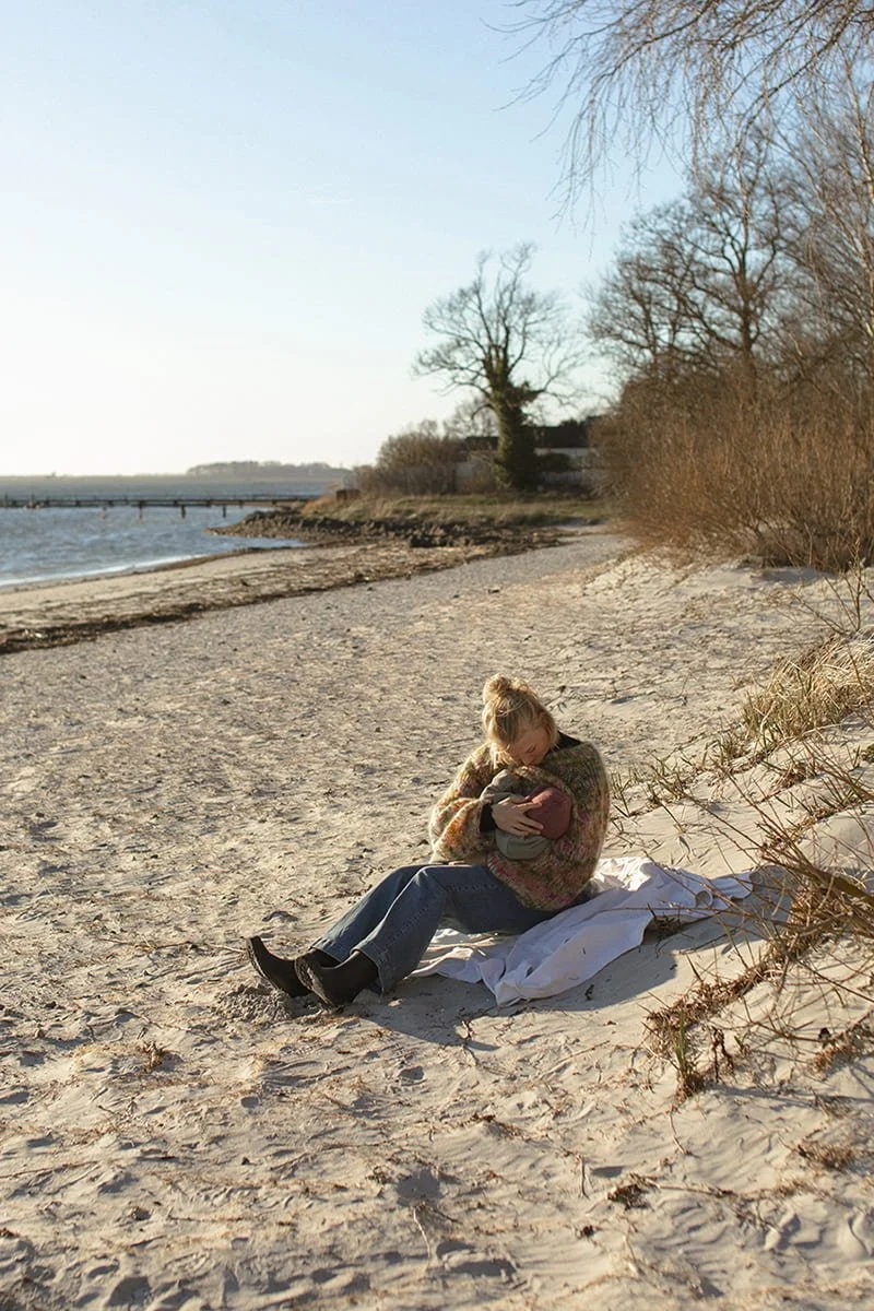 Mamma ammar sin bebis på stranden i Bjärred en solig vårdag.
