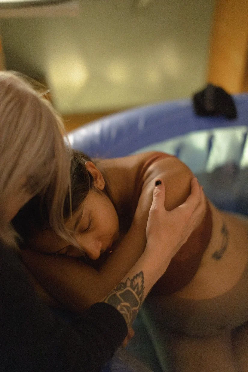 Kvinna under förlossning i vatten med partner vid sin sida