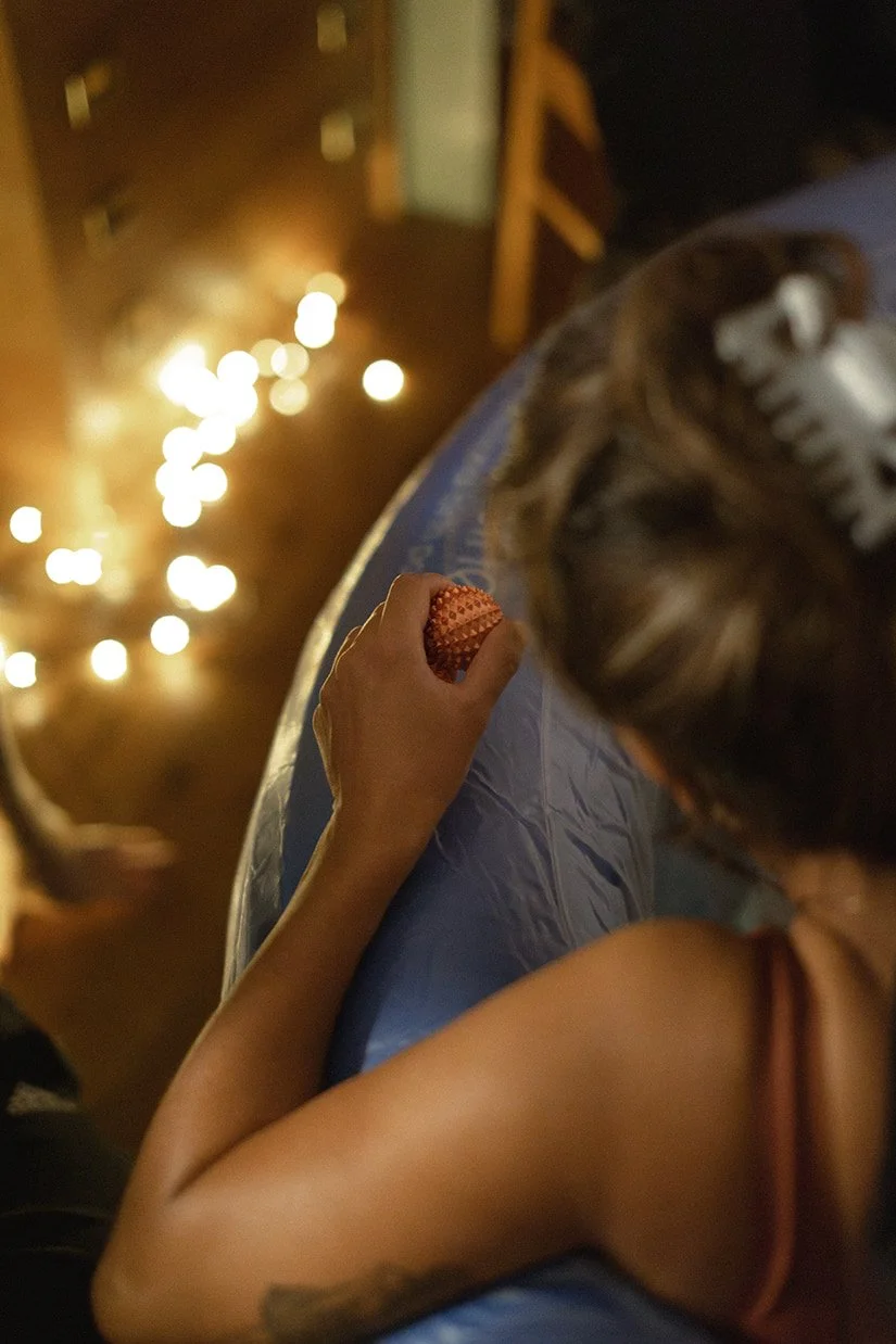 Kvinna under förlossning som håller i en massageboll i förlossningspool