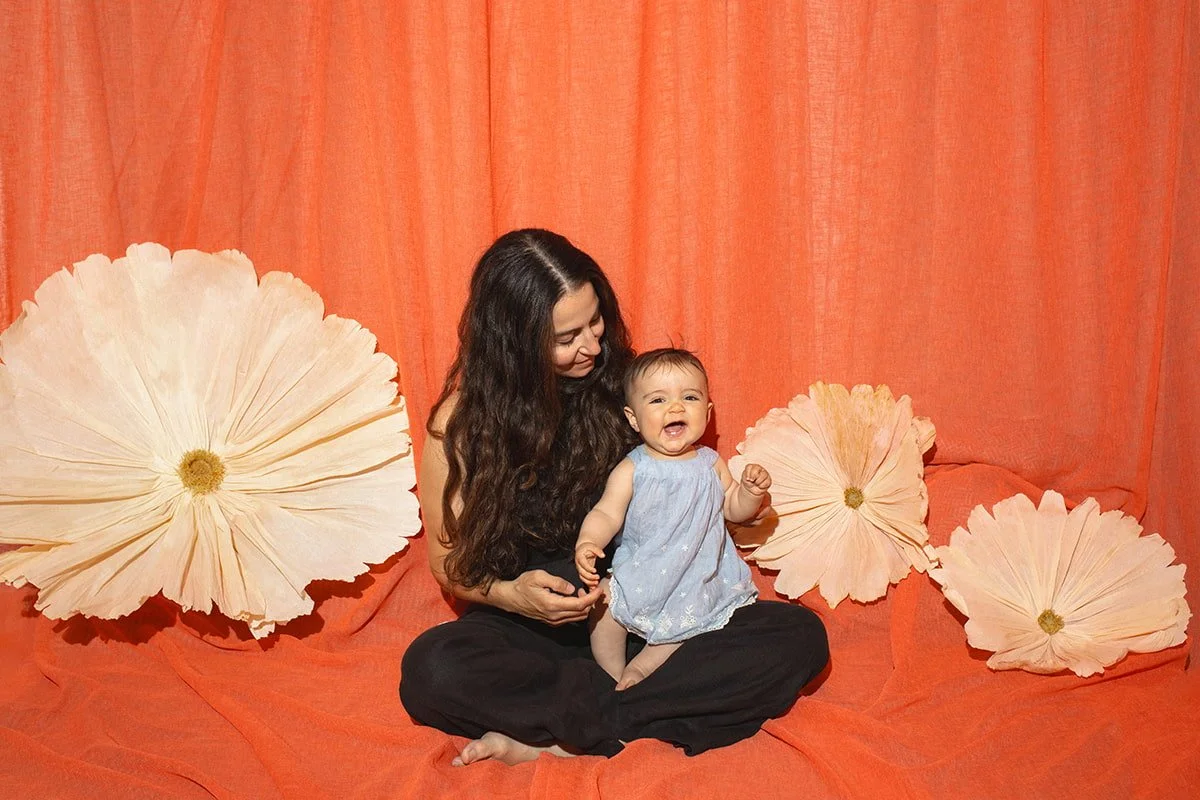Mother and baby during a relaxed family photography session in Malmö. Natural motherhood portrait with artistic floral styling and soft connection.
