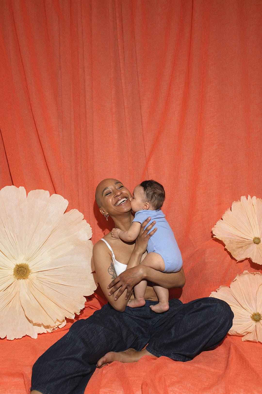 Mother laughing while holding her baby during a motherhood photography session in Malmö. Warm and artistic family portrait, perfect as a Mors Dag present or baby photography experience.