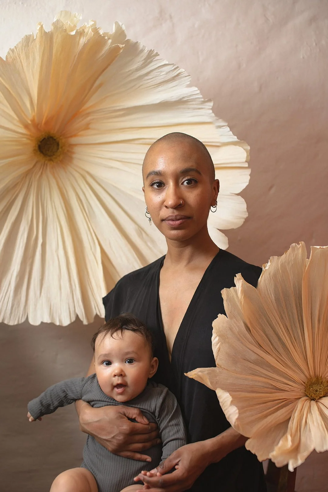 Mother holding her baby during an artistic motherhood photography session in Malmö. Natural family portrait with oversized paper flowers, created as a calm and meaningful Mors Dag photography experience.