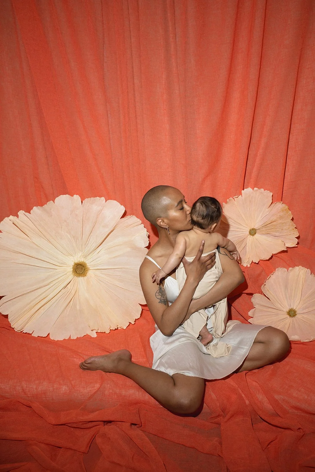 Mother and baby embracing during an artistic motherhood photography session in Malmö. Warm, creative family portrait with floral backdrop, inspired by connection, care and Mors Dag photography experiences in Malmö