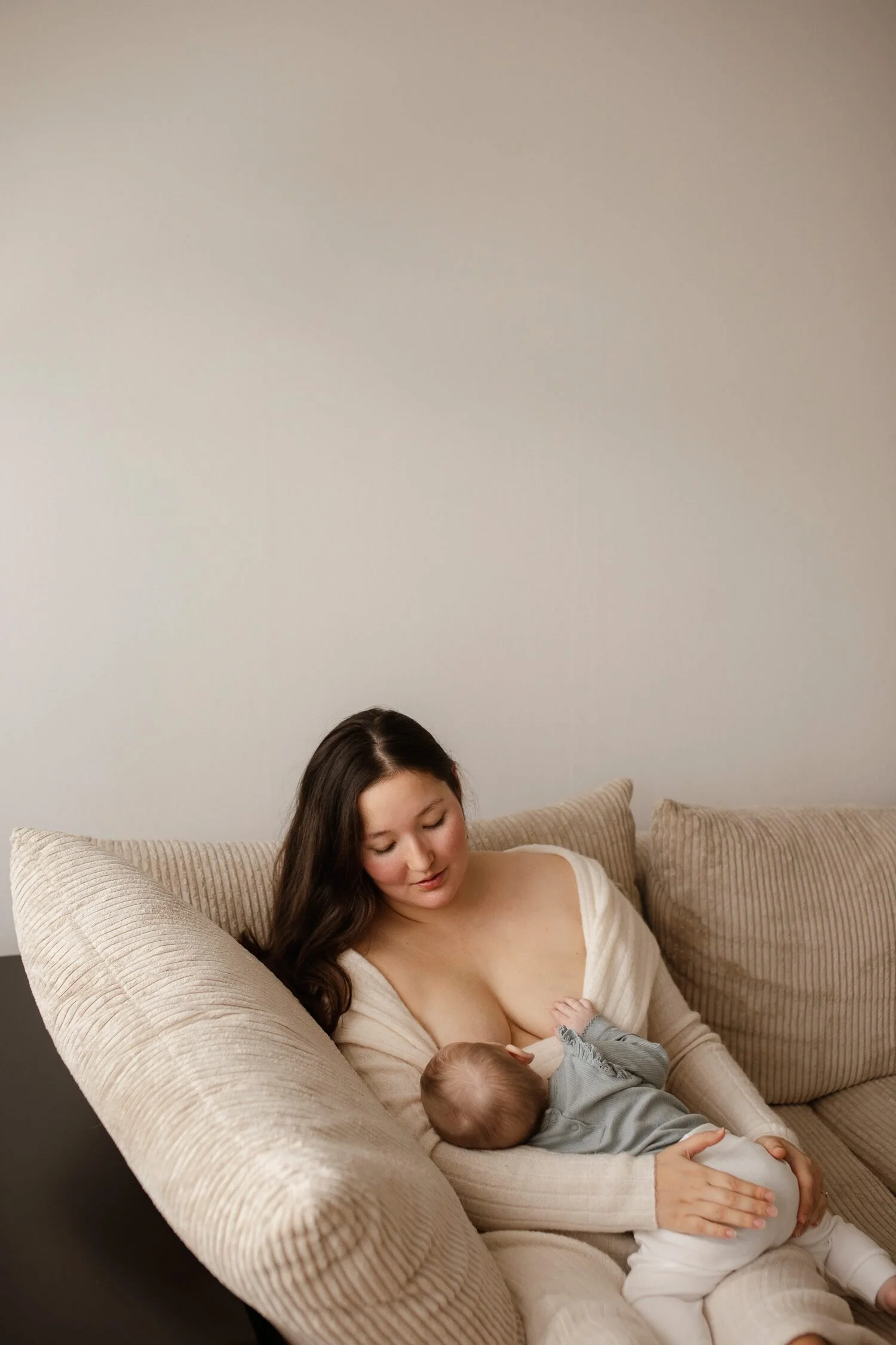 Mamma som ammar sitt nyfödda barn hemma i naturligt ljus