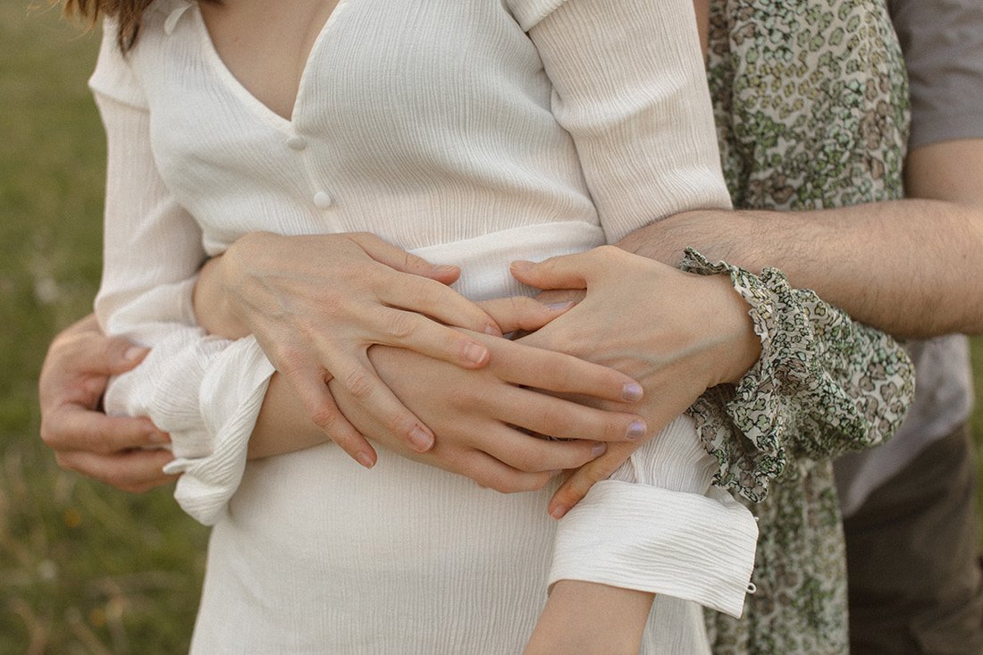 Närbild av händerna på en tonårsdotter och hennes föräldrar som håller varandra i handen under en familjefotografering i Lund, Skåne.