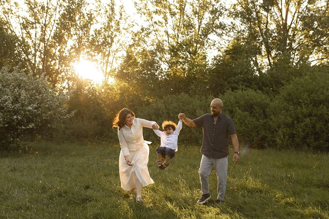 Familj i solnedgång på blommande äng i Skåne under vårfotografering