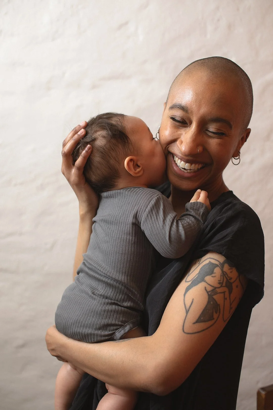 Smiling mother holding her baby during a natural motherhood photography session in Malmö. Emotional family portrait capturing closeness, joy and everyday connection.