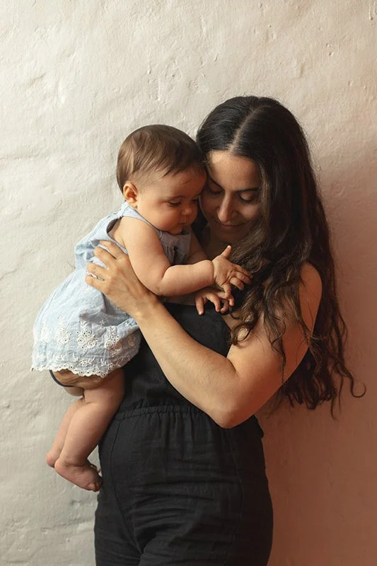 Mother and baby during a relaxed family photography session in Malmö. Natural motherhood portrait with artistic floral styling and soft connection.