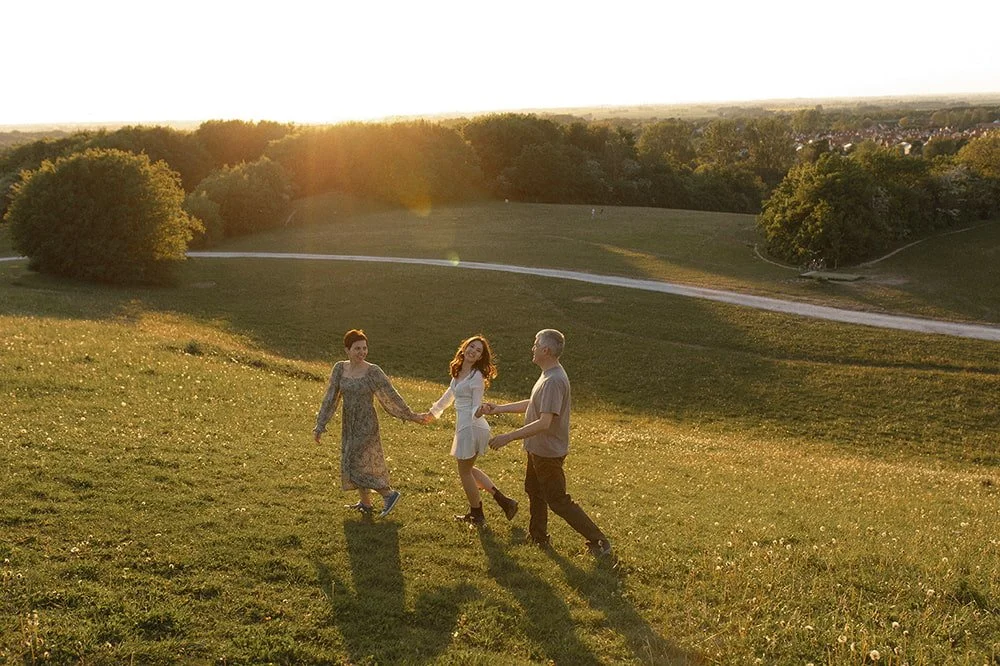 Familj med tonårsdotter går hand i hand i varmt kvällsljus