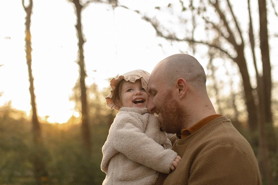 Pappa håller sin bebis i famnen och de skrattar tillsammans