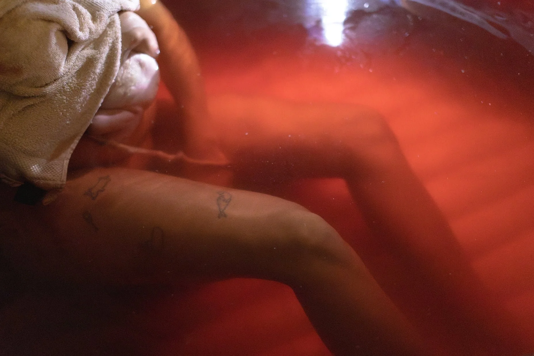 Hemförlossning i vatten – födande kvinnas ben i förlossningspool med blod i vattnet