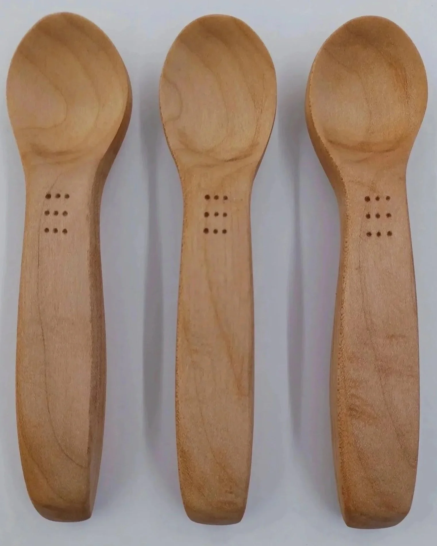 Three Western Maple wooden spoons with thumb placement indents and thick handles to aid grip for persons with reduced dexterity