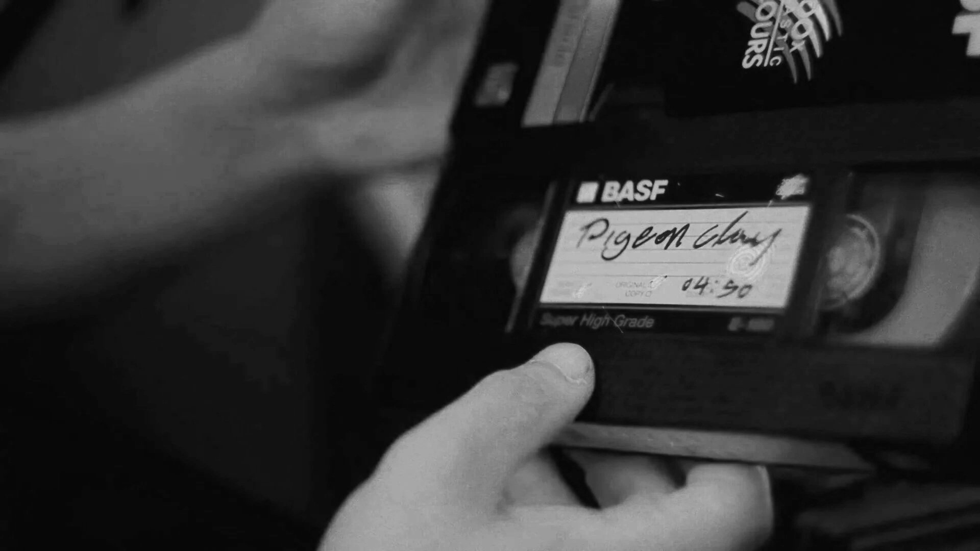 Imagem em preto e branco de uma pessoa segurando uma caixa de notification de um produto da BASF com o rótulo 'Pigeon Clay' e horário 04:50.