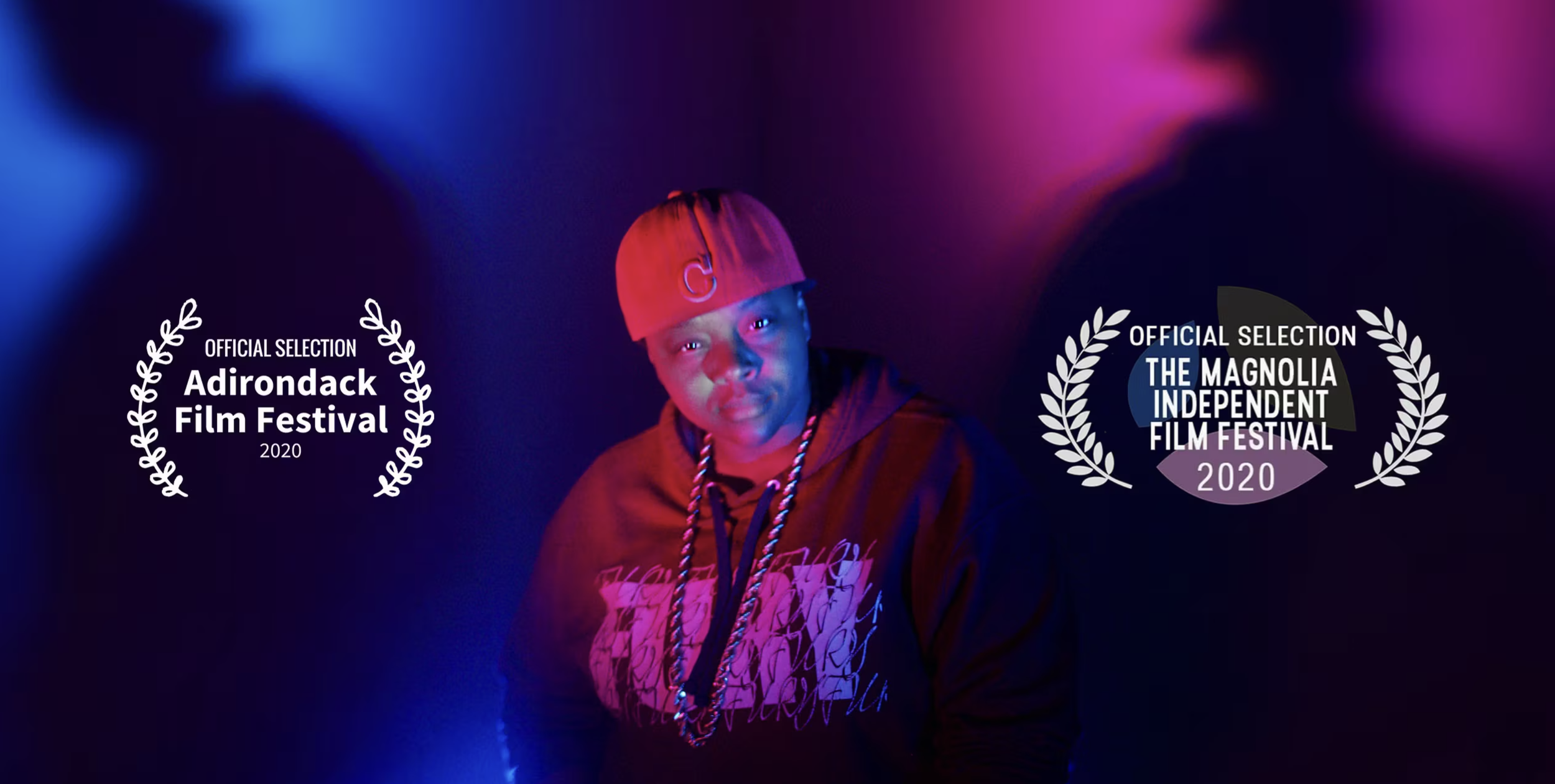 A person wearing a red cap and a hoodie, illuminated by blue and purple lighting, with film festival laurels and text indicating selections from the Adirondack Film Festival and Magnolia Independent Film Festival in 2020.