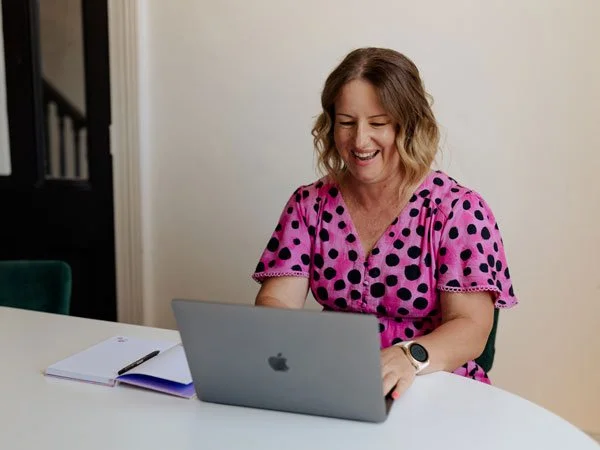 ness working at a laptop, smiling
