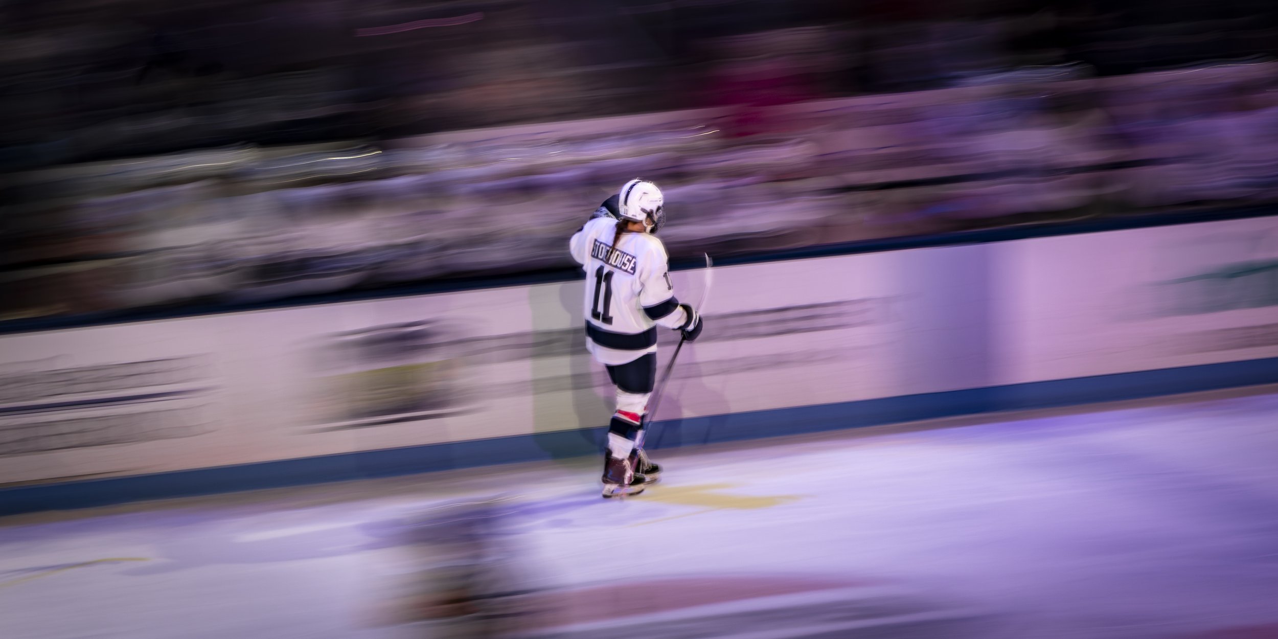 Ice hockey player in a white jersey with the number 11 skating on the ice inside an arena.