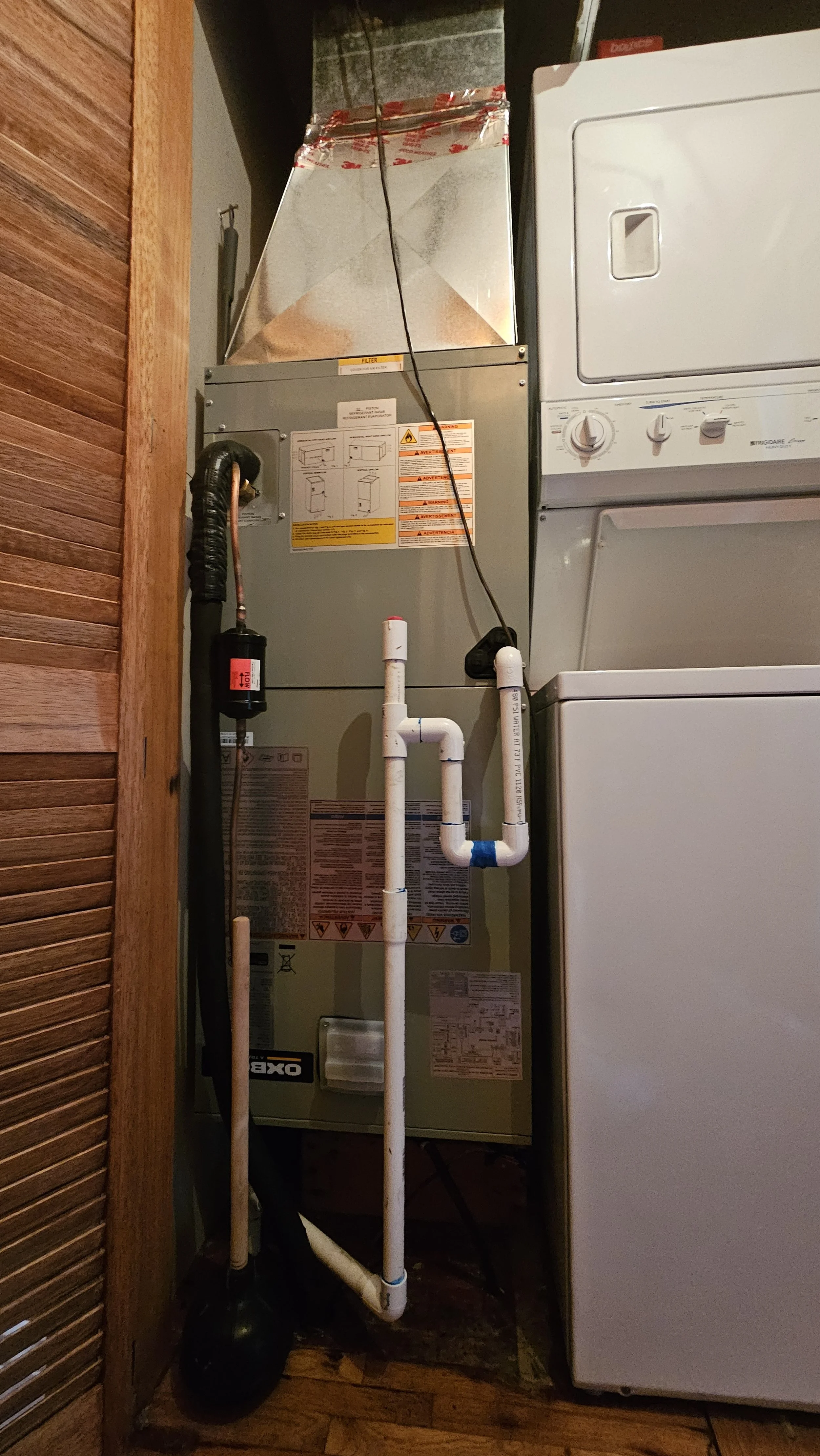 View of a furnace or HVAC unit with pipes, a black float, and a laundry washer and dryer on the right side.