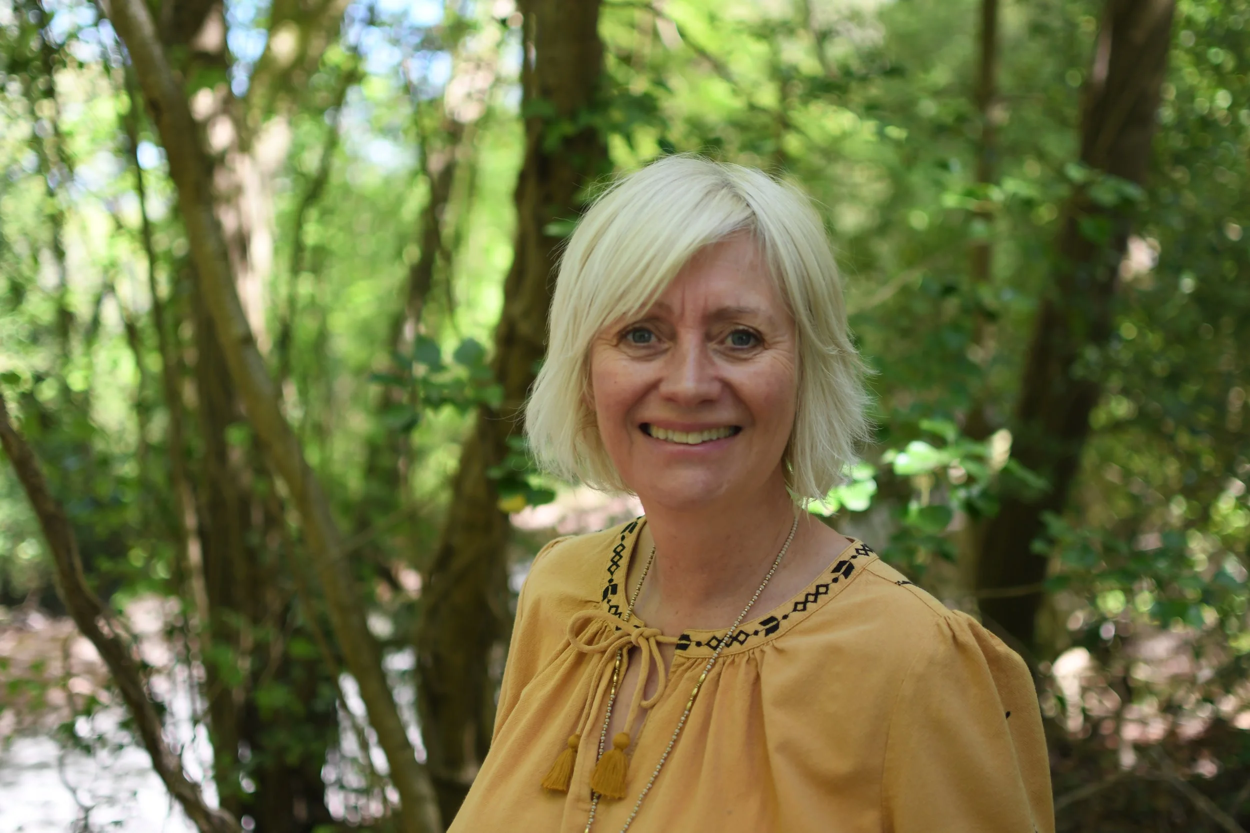 A woman with blonde hair in the woods
