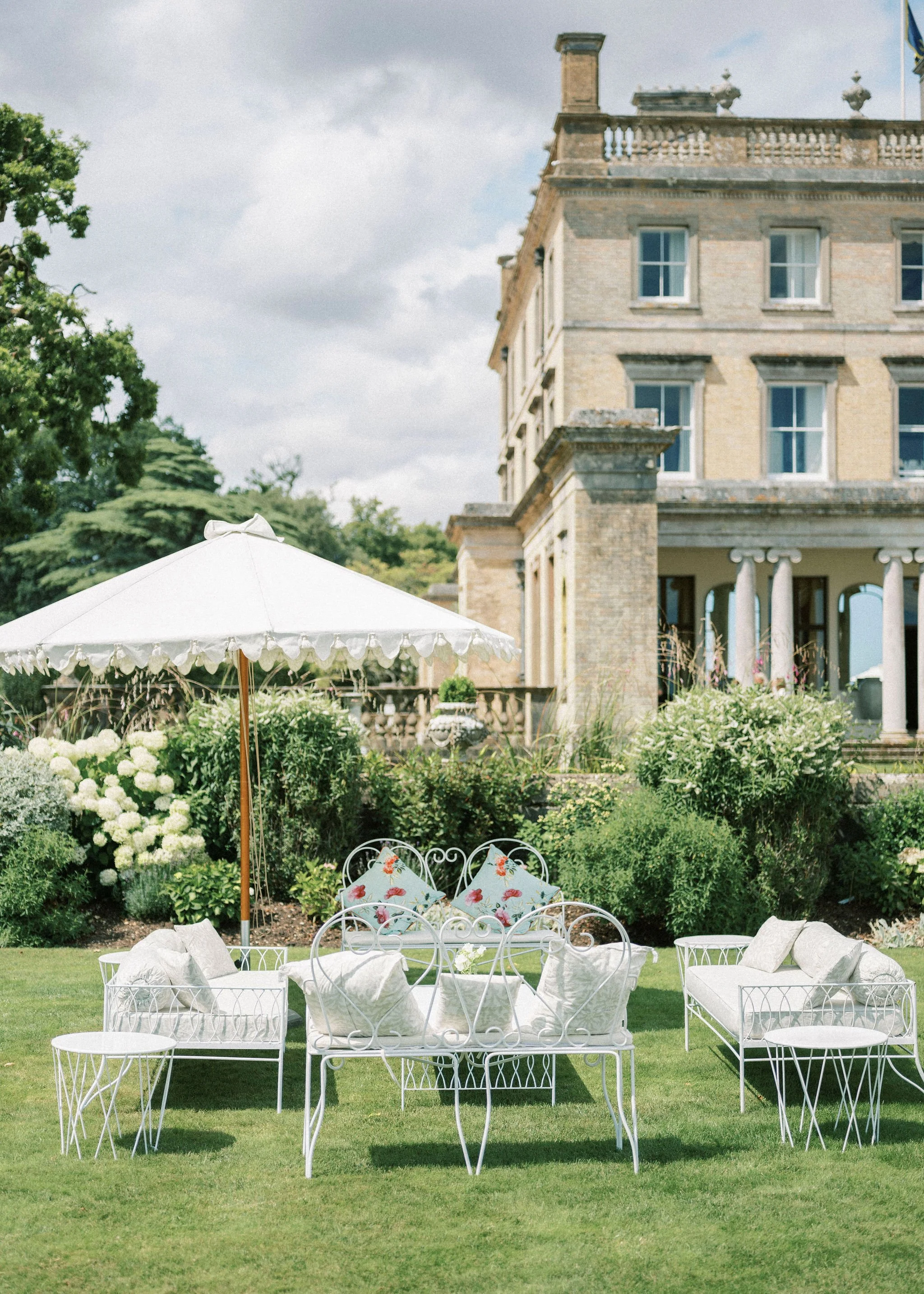 somerley house lawn set for a wedding reception with white iron furniture and stylish parasols