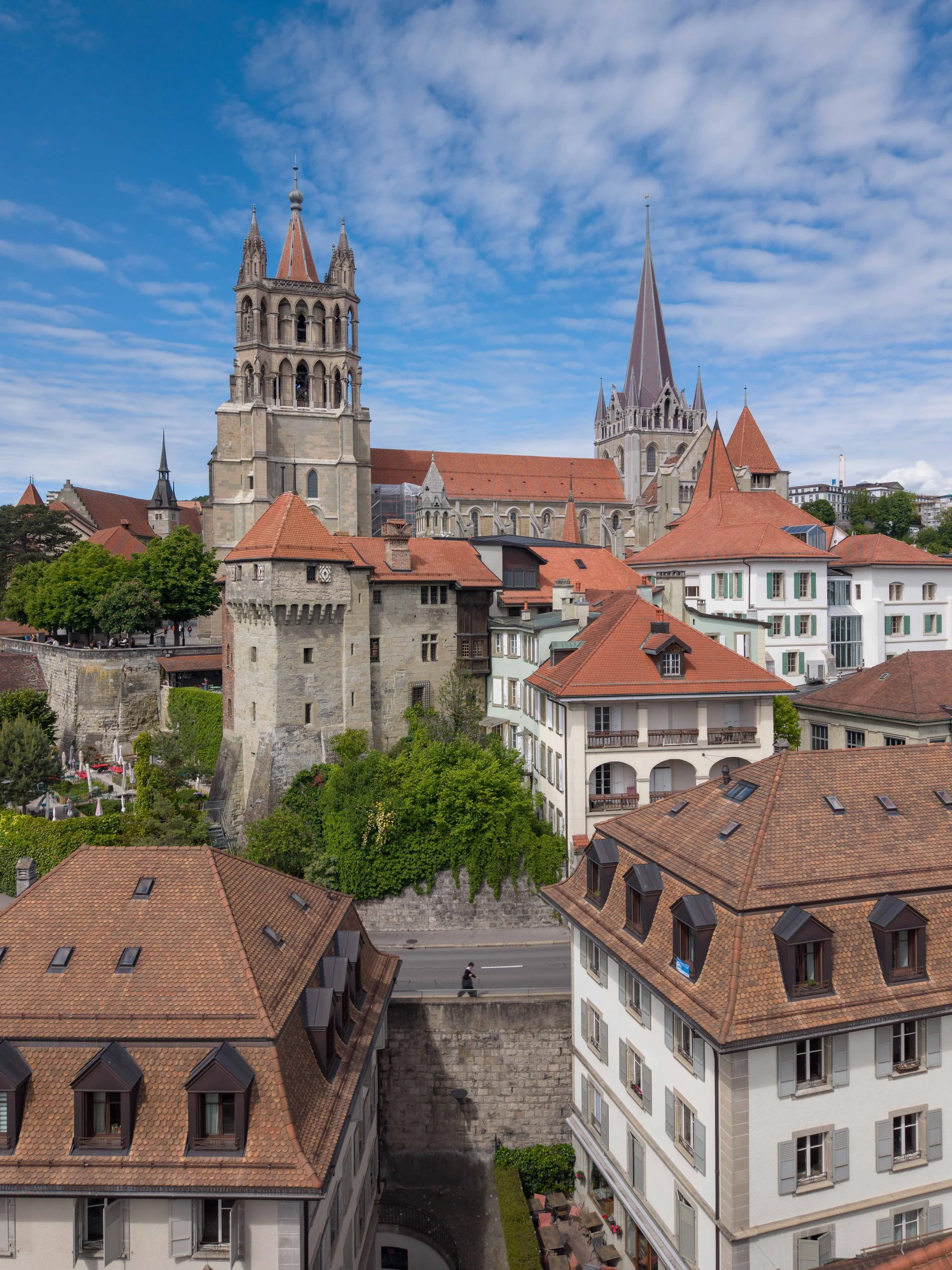 Une ville with des bâtiments historiques et une église avec deux tours, sous un ciel bleu avec des nuages.