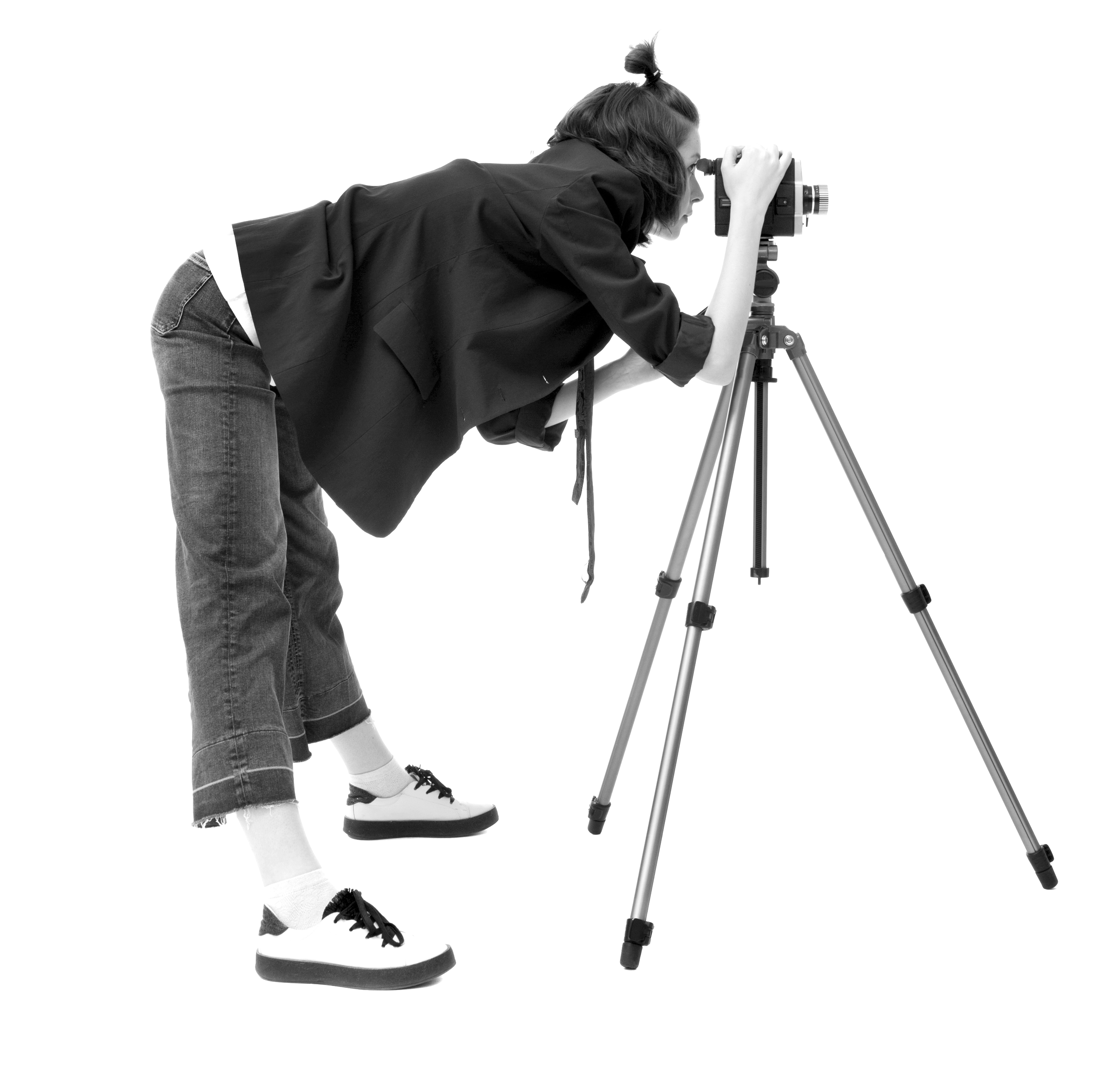 A person leaning forward, looking through a vintage film camera mounted on a tripod, against a minimalistic background.