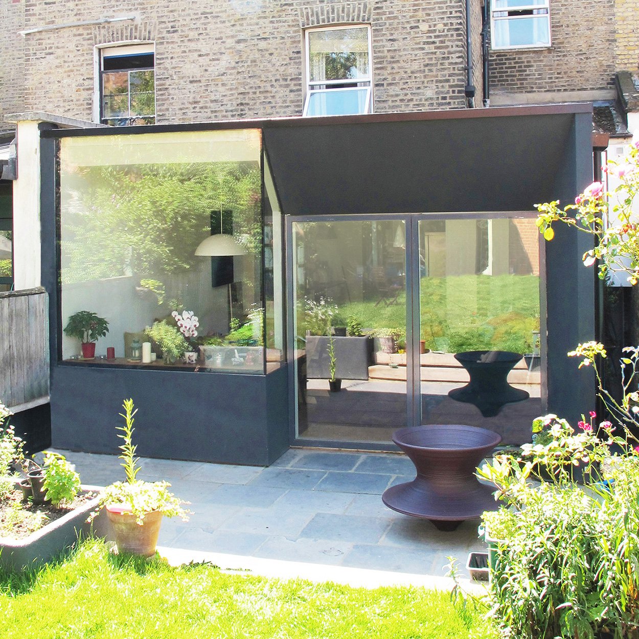 Modern glass extension on a brick house with garden