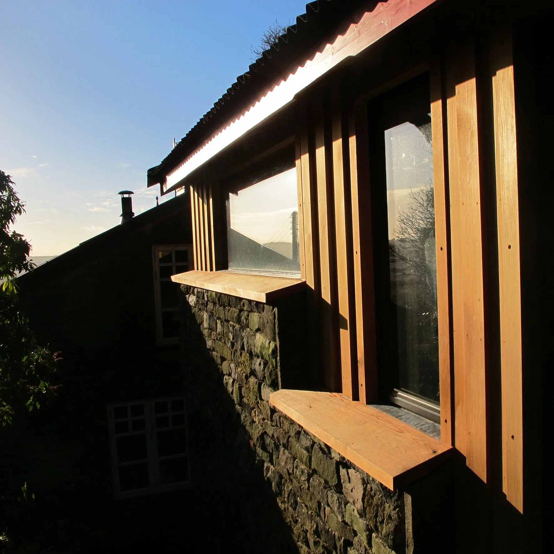 A close up view of vertical red cedar cladding to a new addition to a house in the peak district under sunny skiess