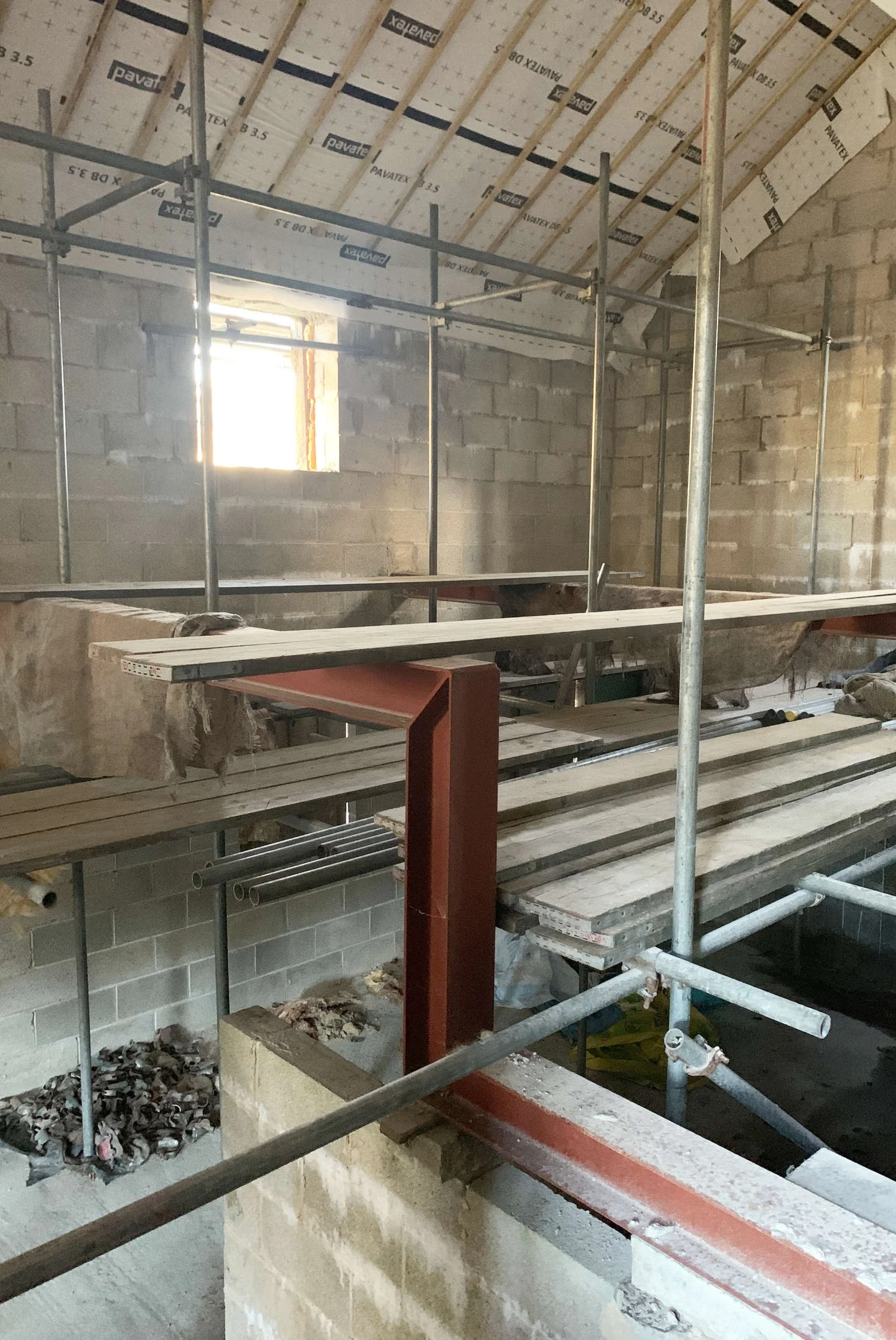 Site photograph of a barn conversion interior showing the bare construction materials of steel beams and stone walls