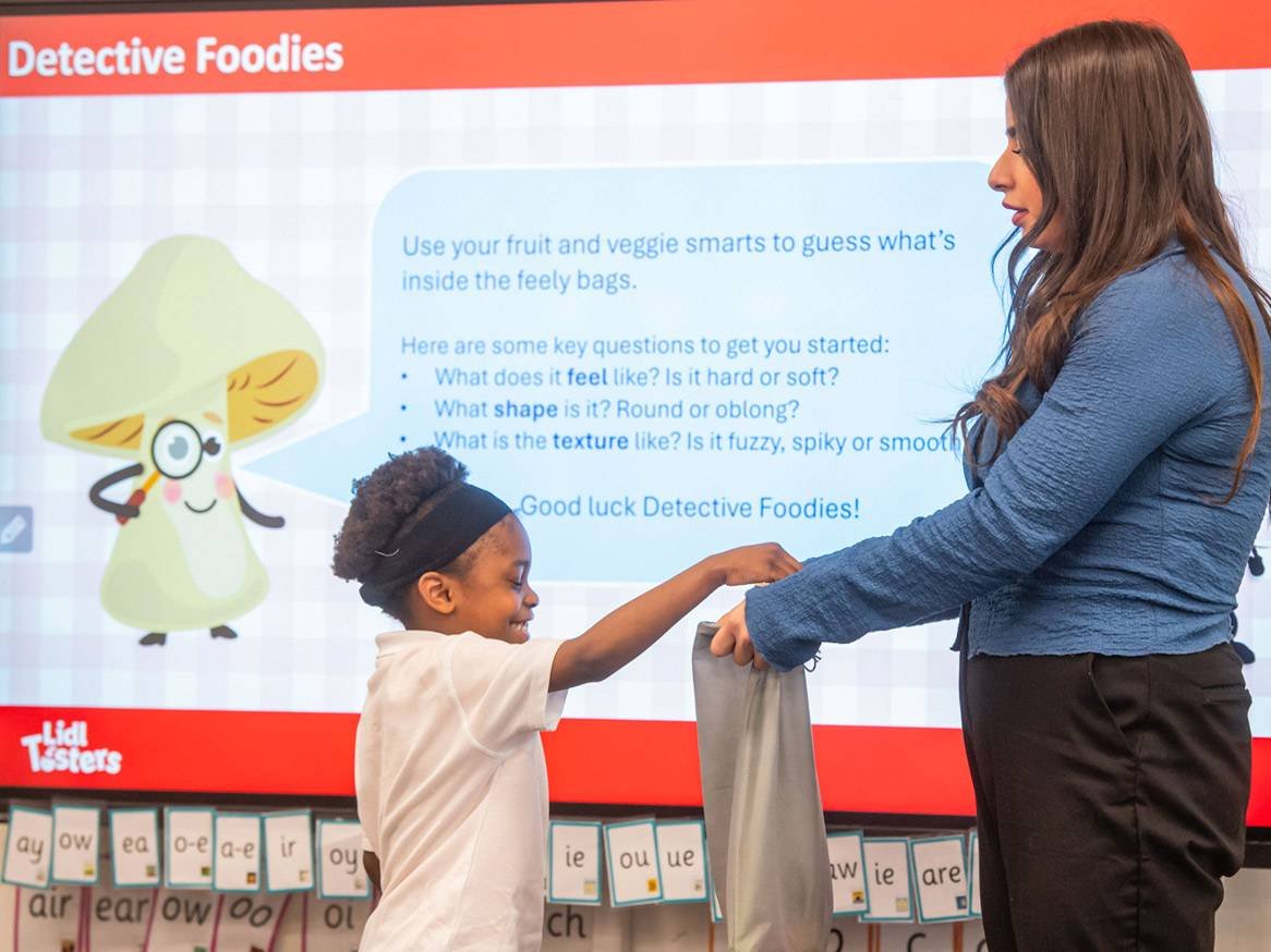 Child at the front of class reaching inside a bag