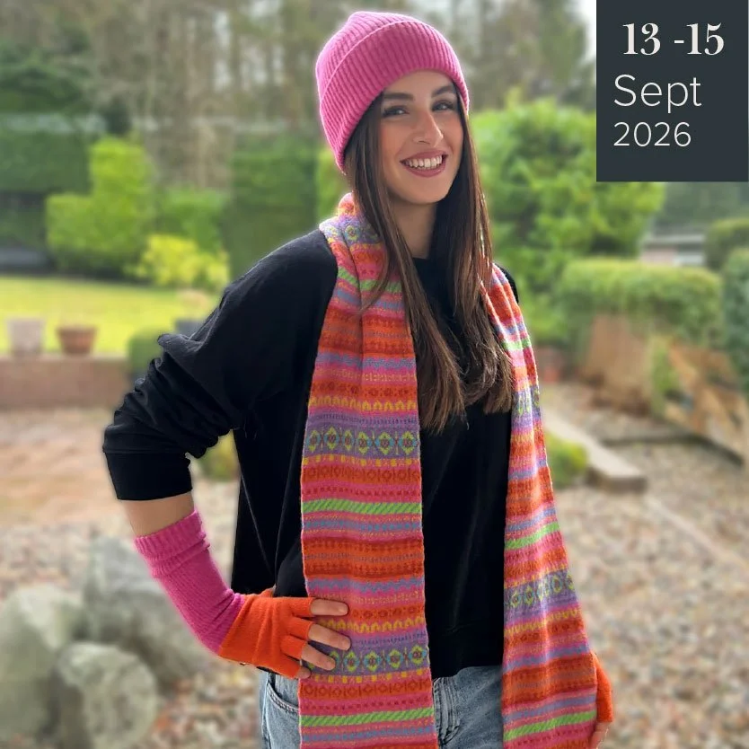 Youn female wearing a bright colourful, pink, fairisle scarf and pin woolen beanie hat by green Grove Weavers