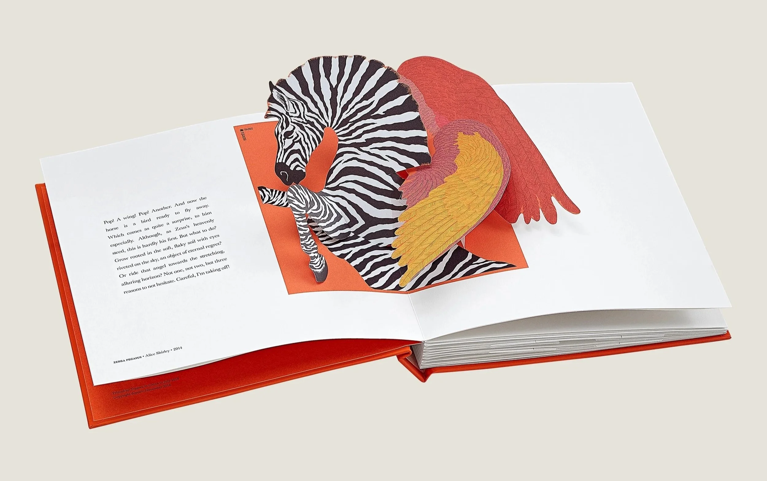 Open book by Hermes with a pop-up illustration of a zebra and a bird with red and yellow feathers.
