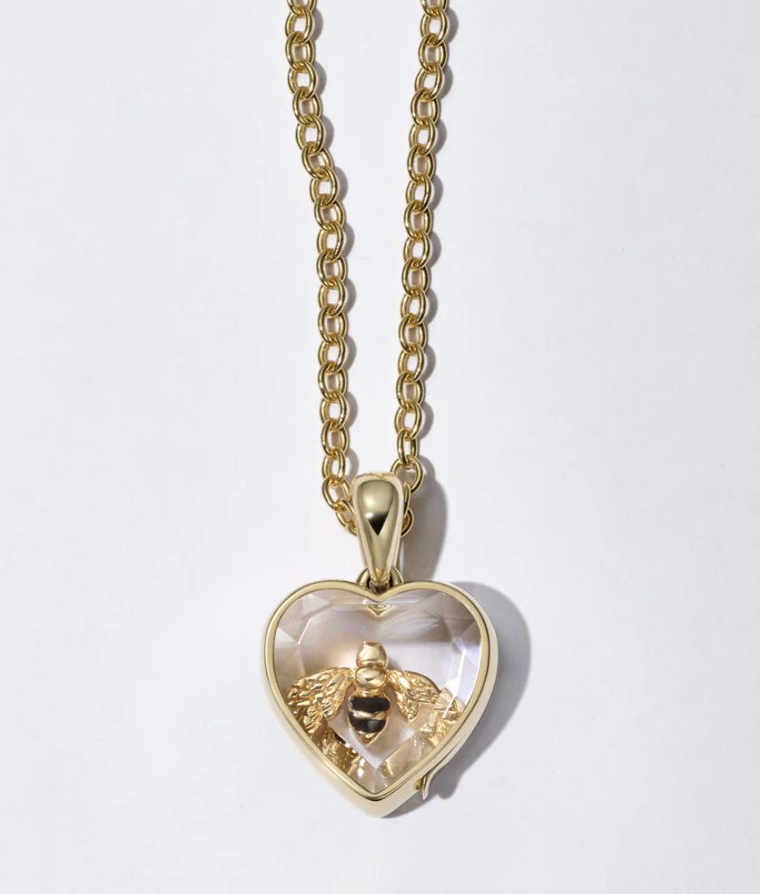 Gold chain necklace with a heart-shaped pendant featuring a small bee inside.