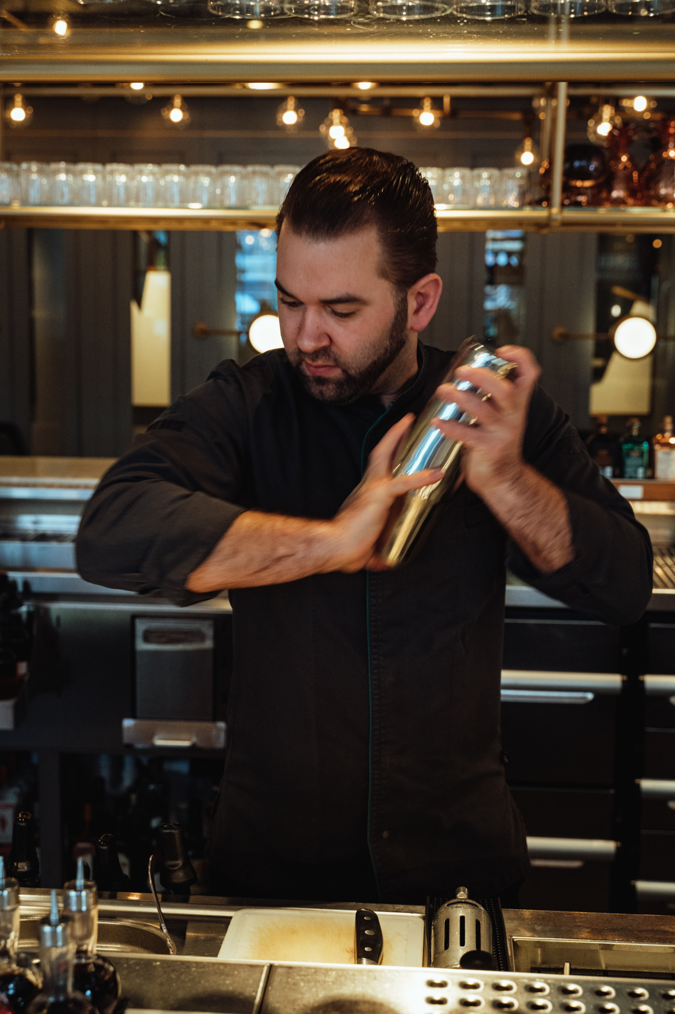 Ein Mann schüttelt einen Cocktail-Shaker in einer Bar.