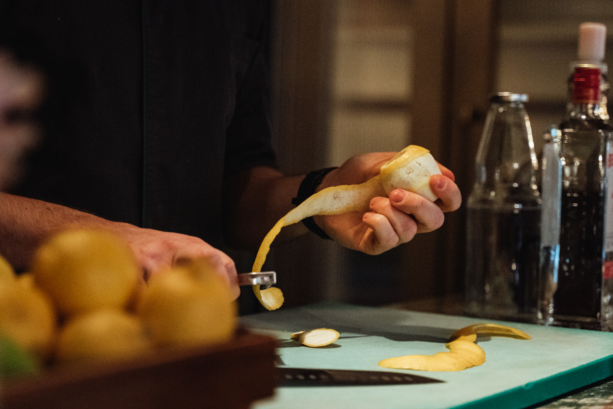 Eine Person schält eine Yacon-Wurzel auf einer Küchenarbeitsfläche, um das Innere freizulegen; im Vordergrund sind andere Yacon-Wurzeln sichtbar, im Hintergrund befinden sich Flaschen und ein Messer.