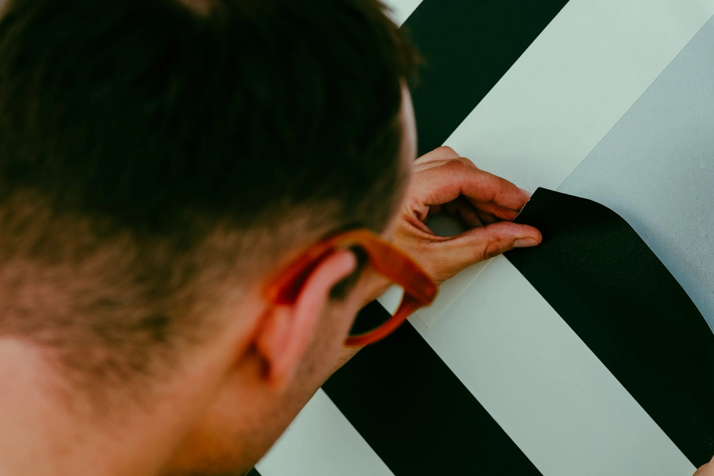 Nahaufnahme einer Person, die eine schwarze Klebebandrolle auf eine weiße Oberfläche klebt.