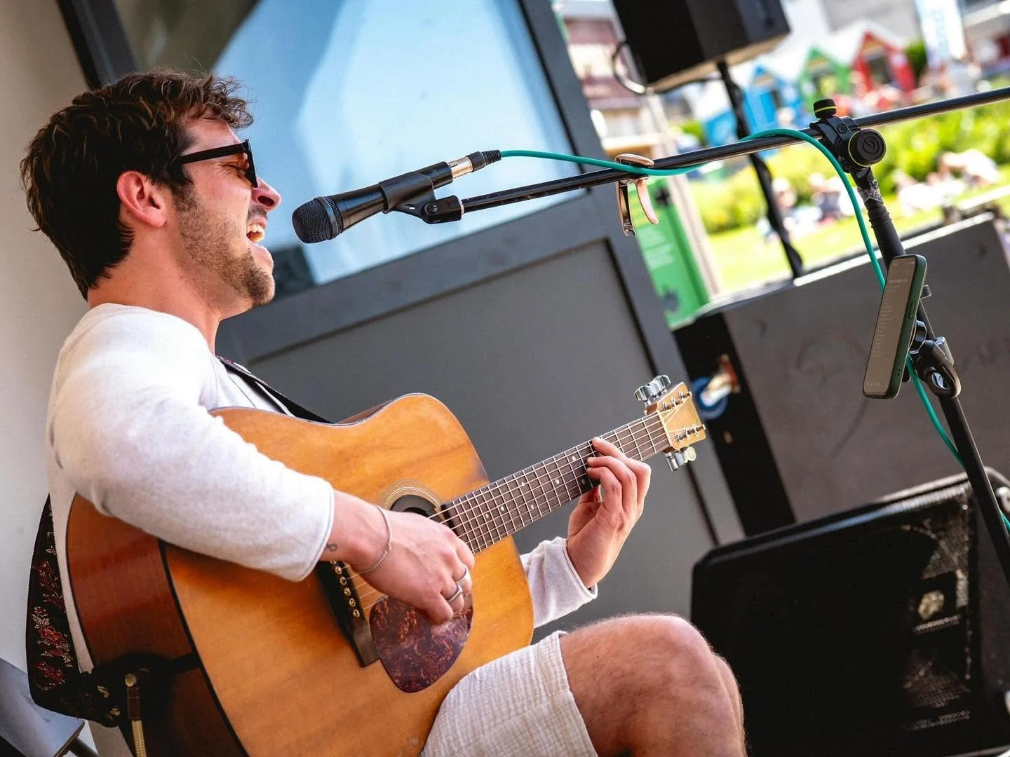 joe hurworth singing while sitting on a chair with sunglasses on